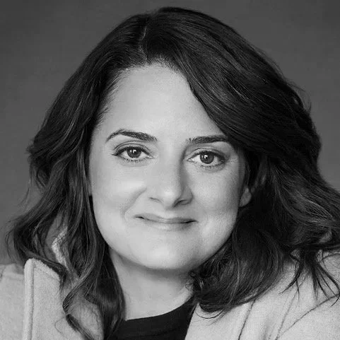 Black and white portrait of a woman with wavy hair, smiling gently at the camera.