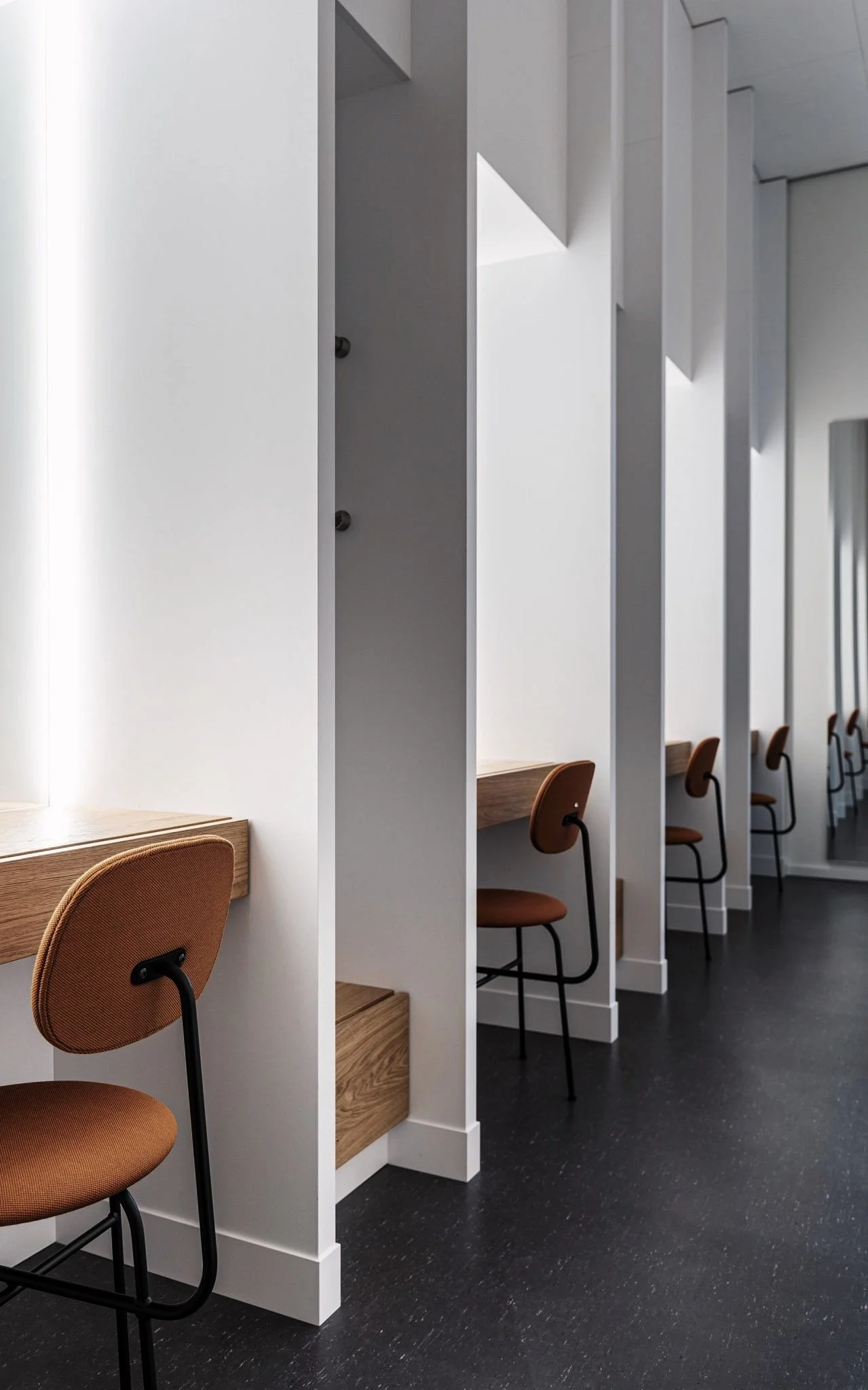 Binnenruimte met schrijftafels en bureaustoelen gescheiden door witte scheidingswanden.