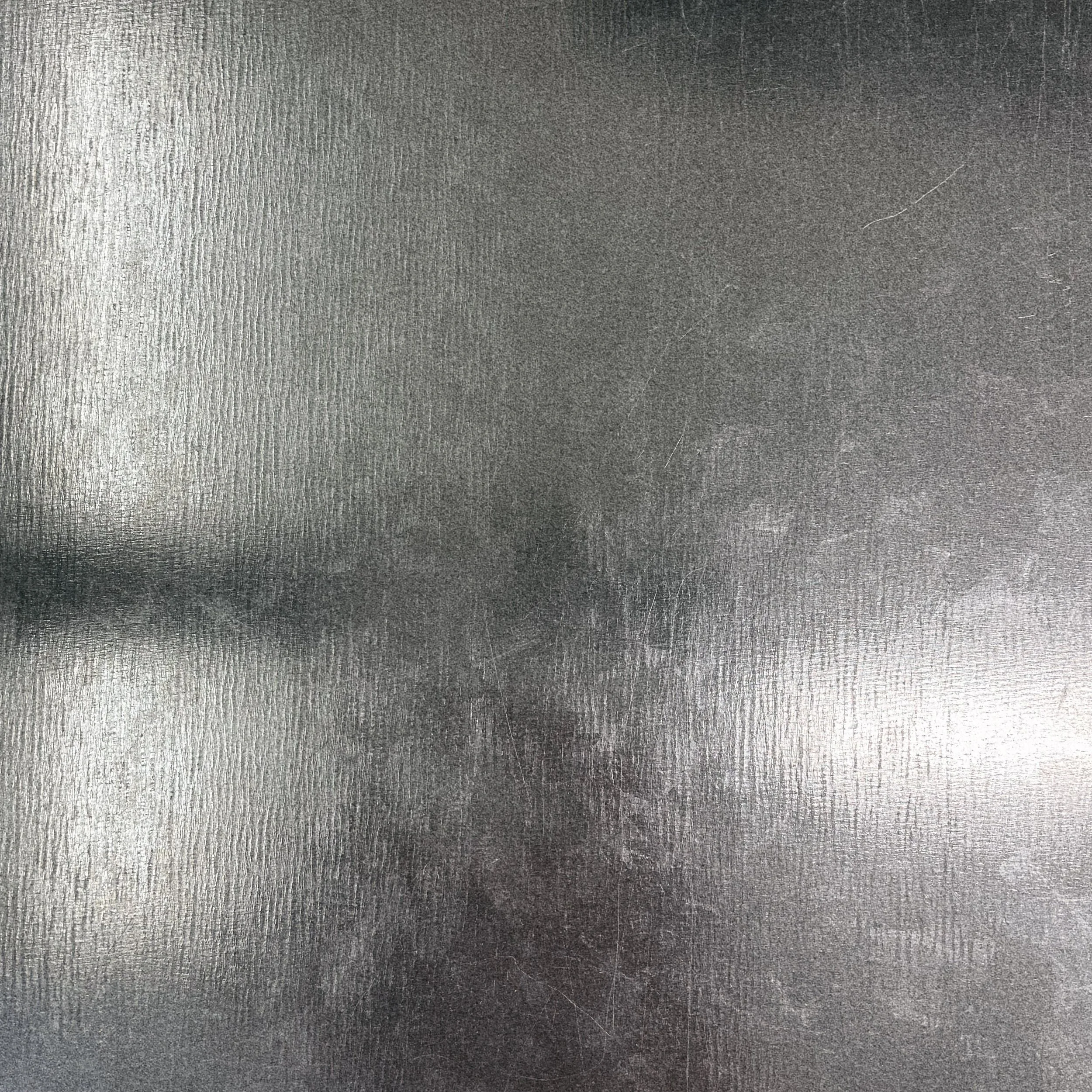 Een close-up afbeelding van een metalen oppervlak met een textuurlicum en lichte krassen.