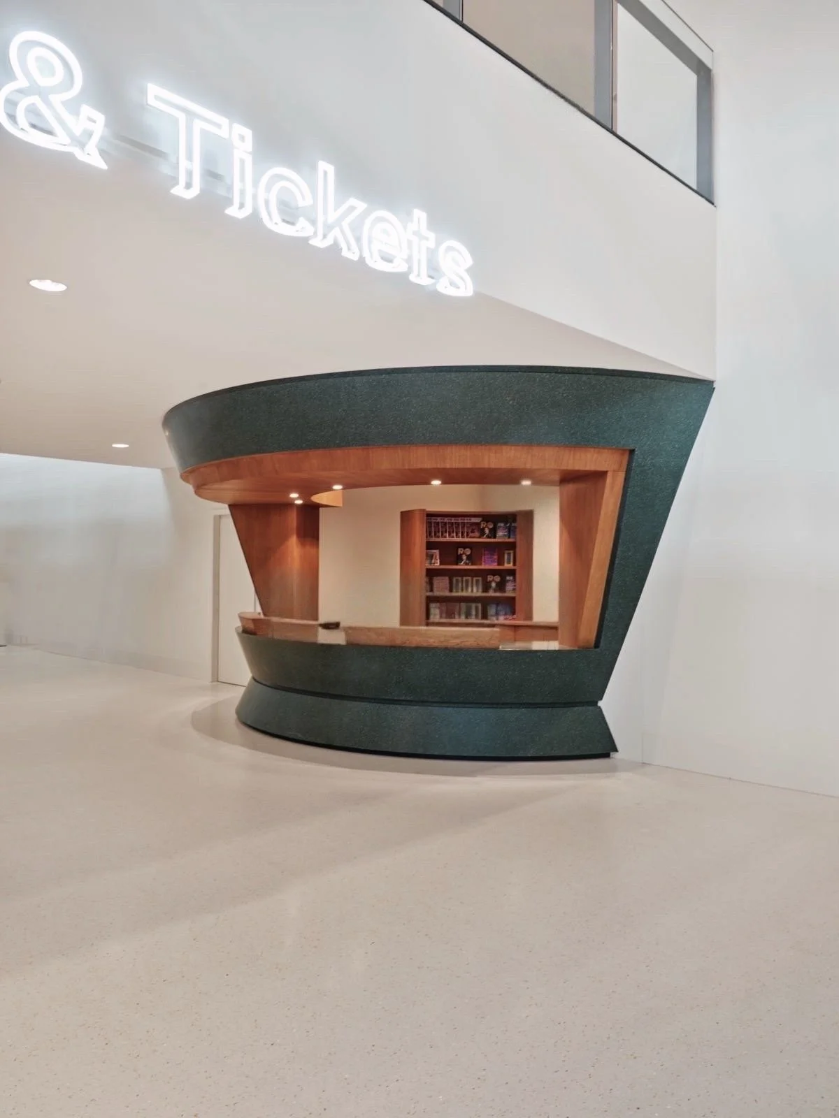 Vriendelijk verkoopbalie in een modern, wit interieur met een neonborden die 'Tickets' aangeven.