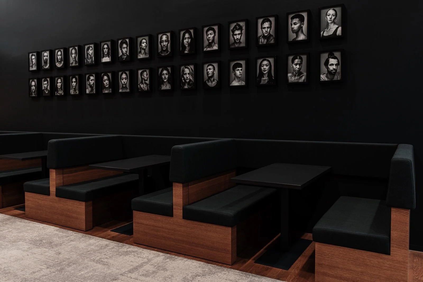 Zwart café of lounge met een muur met zwart-wit portretfoto's en zwarte en houten bankjes.