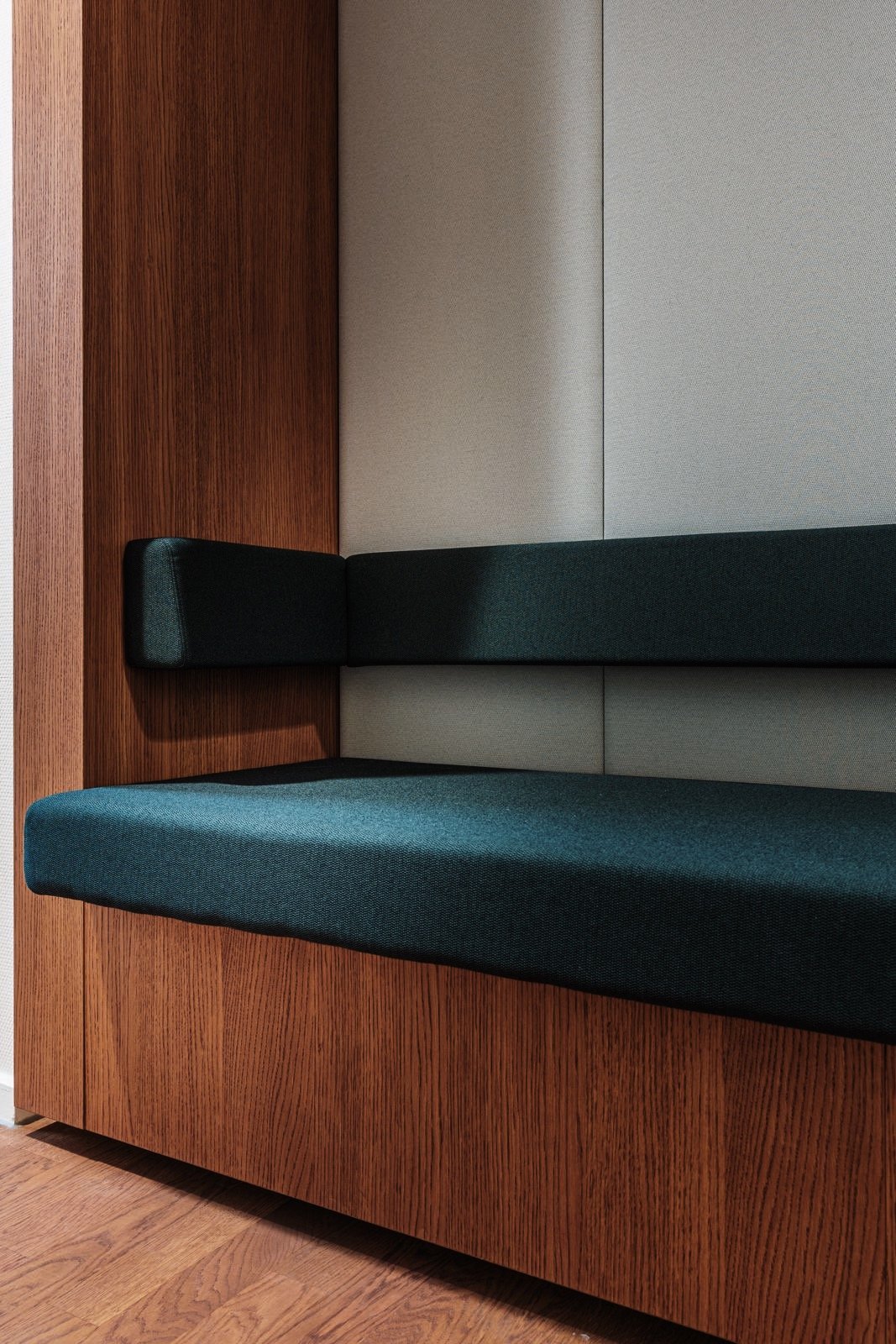 Close-up van een moderne bank met gestoffeerde zitting en rugleuning, gecombineerd met een houten en muurbekleding.