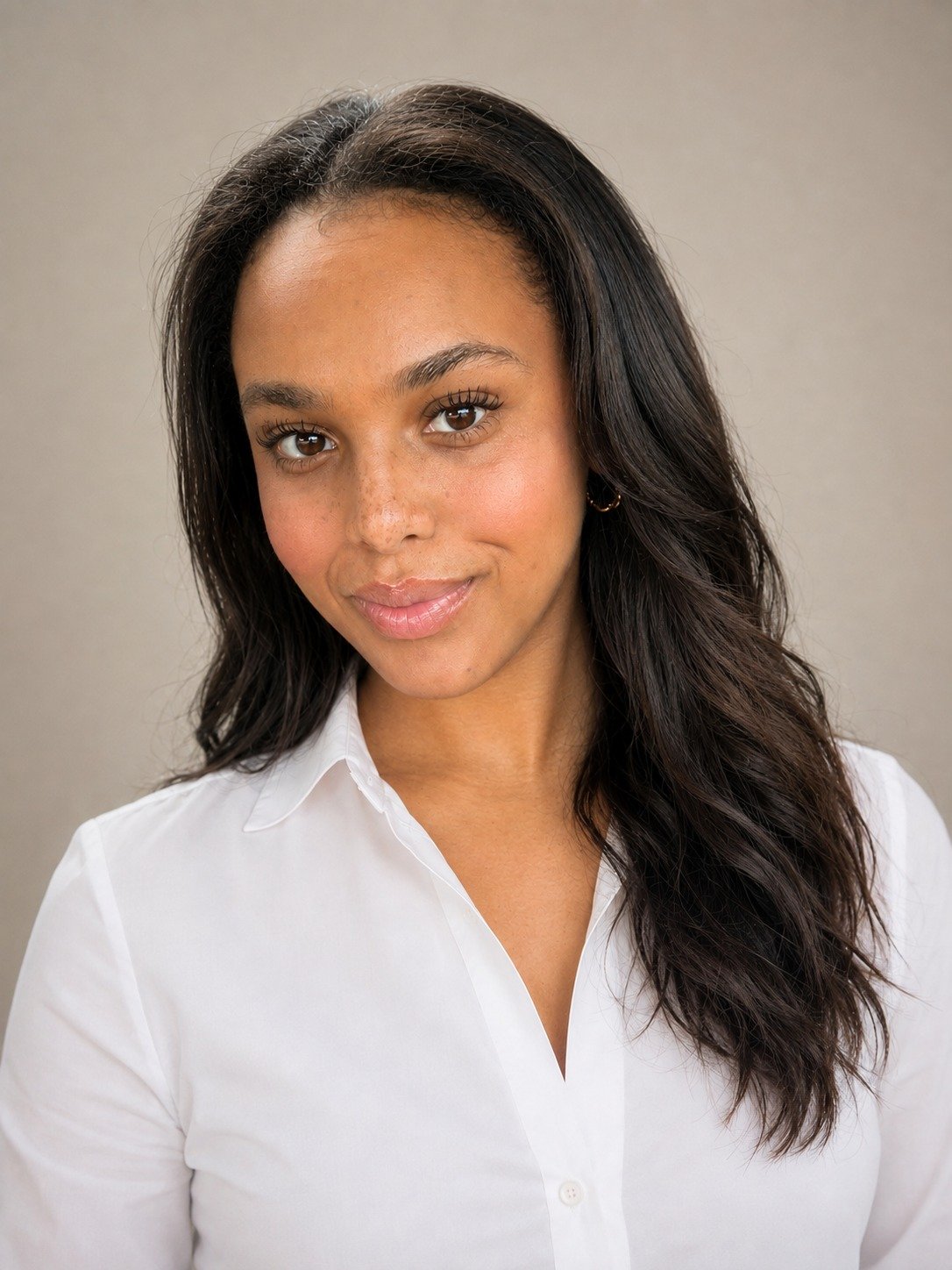 A young woman with long black hair, wearing a white collared shirt, smiling slightly, with a neutral background.