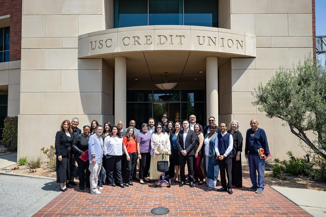 Group of diverse people standing in front of the USC Credit Union building.