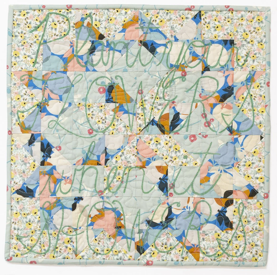 Small square quilt with star design in yellow, green, and blue tones, with the written words "Plant your FLOWERS when it SHOWERS" over the whole quilt