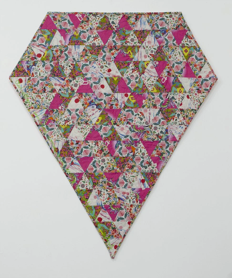 Bright pink quilt made of equilateral triangles arranged in a diamond shape with green text down one side reading "Our actions' unintended consequences easily outnumber a diamond's facets"