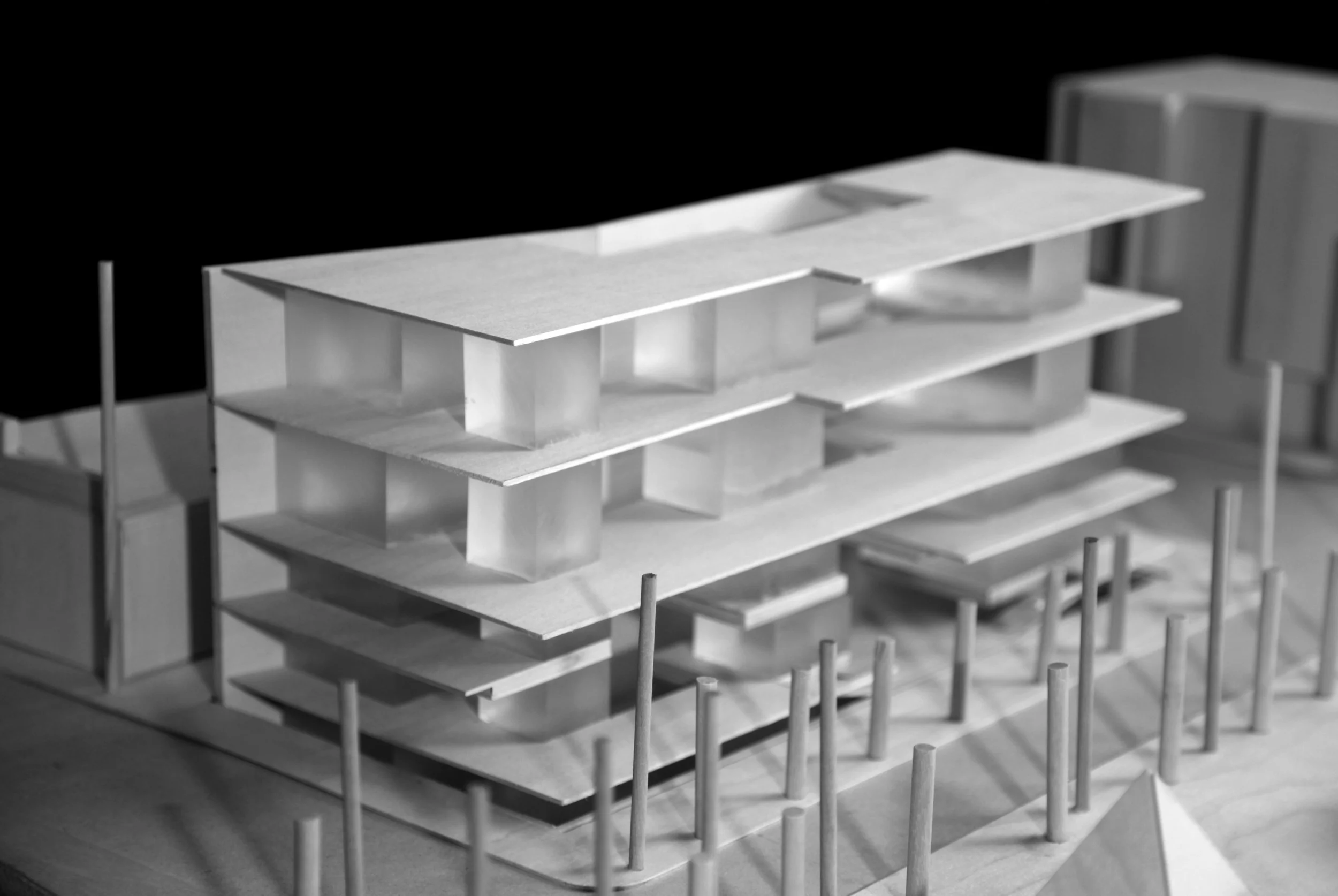 A detailed model of a modern multi-story building made of white material, showing multiple floors, supported by columns, with some interior elements visible.