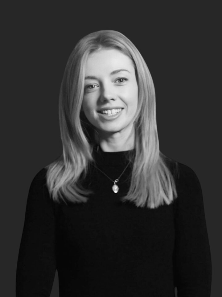 Black-and-white professional portrait of Bex Beaumont, the Head of Content, set against a dark background.