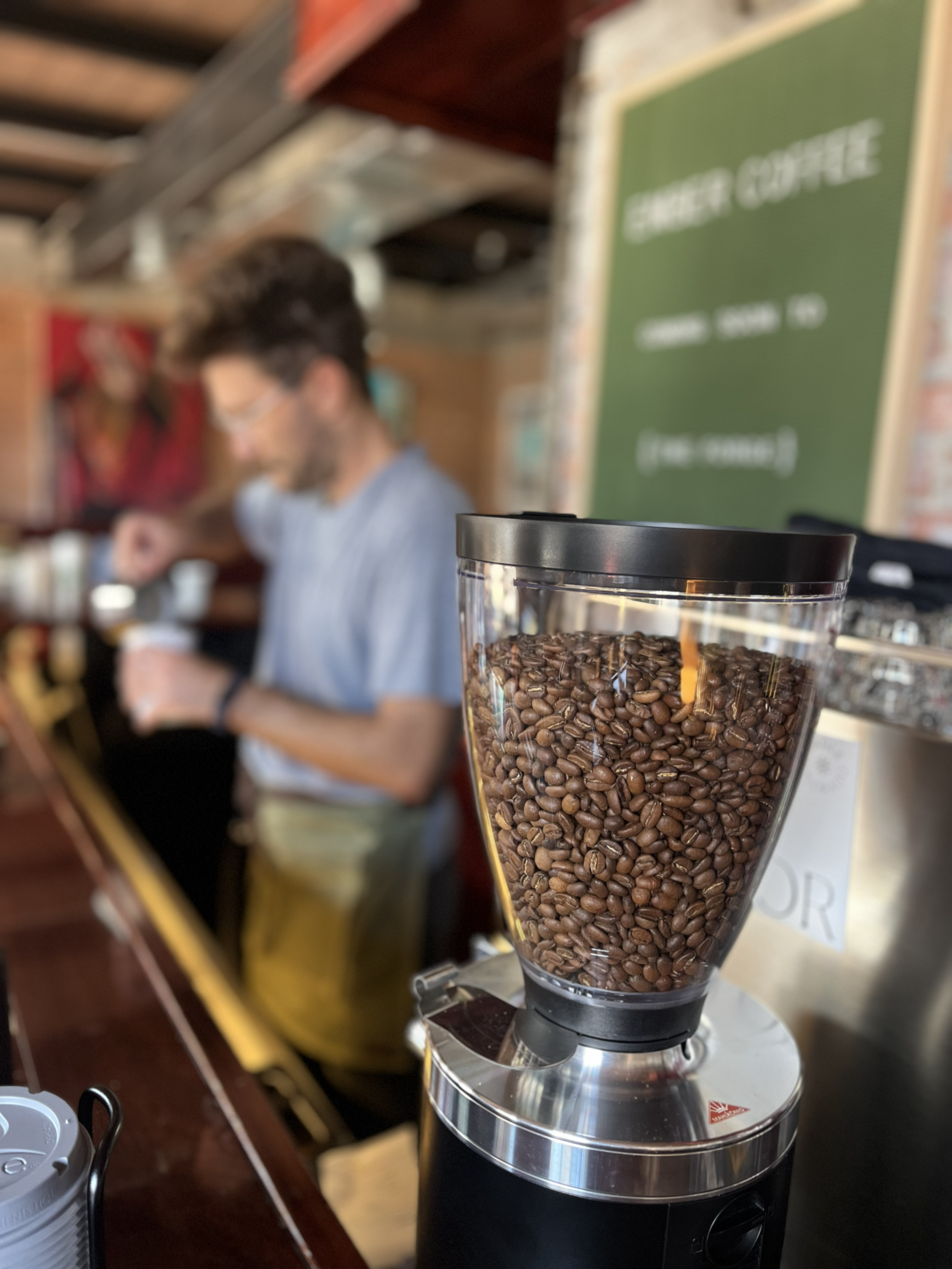 Close-up of a coffee grinder filled with coffee beans in a coffee shop.