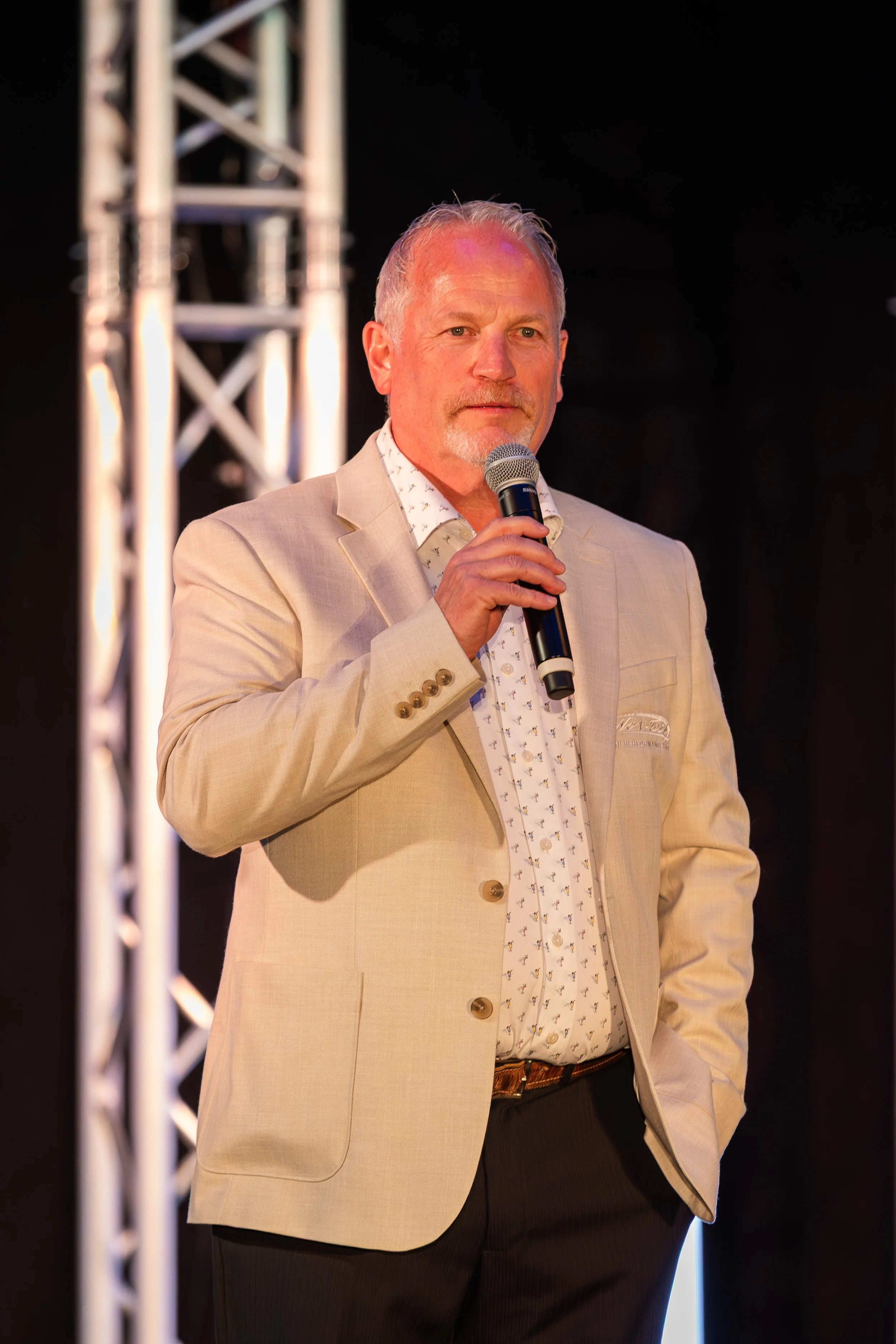 Speaker on stage framed by truss lighting towers in Southwest Florida