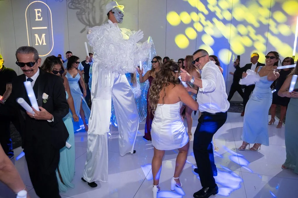 Stilt performer and dancing guests under monogram gobo lighting in Southwest Florida