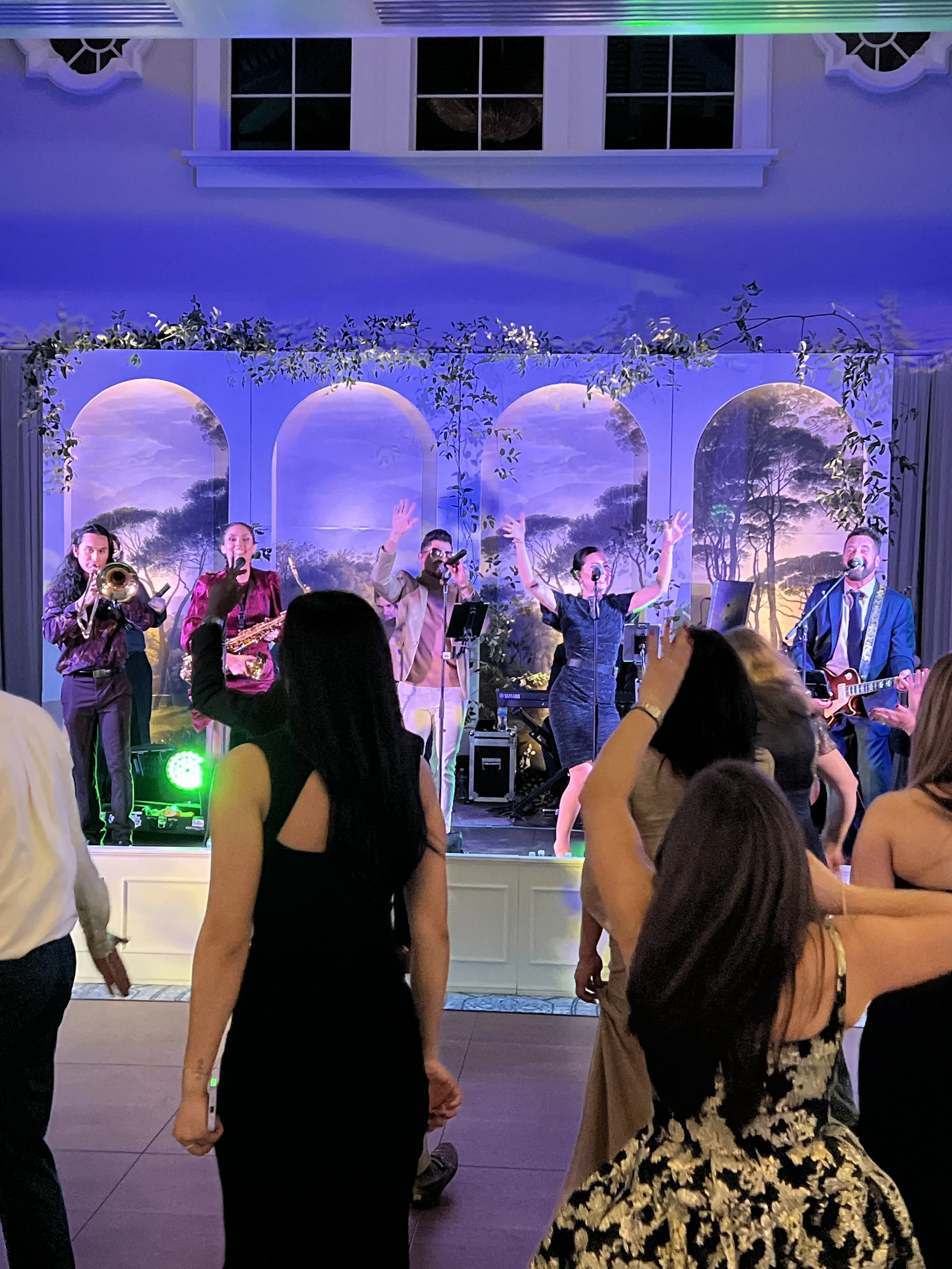 Live band performing on stage with arch backdrop and green uplighting in Southwest Florida