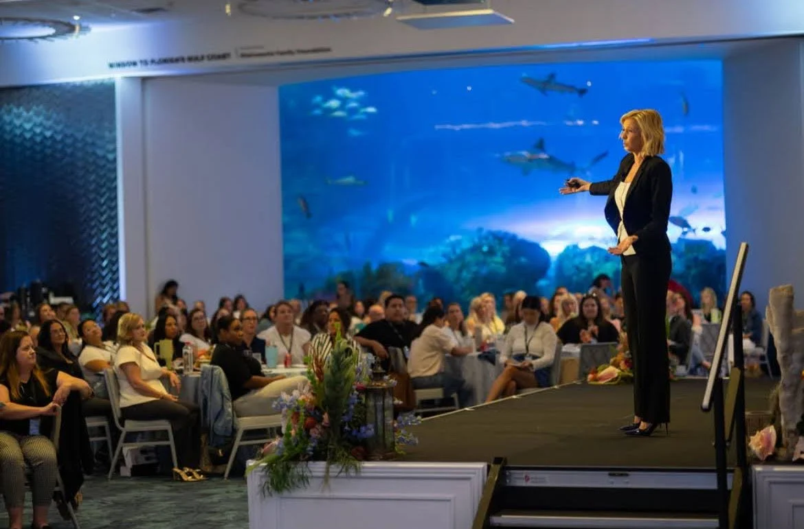 Large-scale screen presentation backdrop for a speaker and audience in Southwest Florida