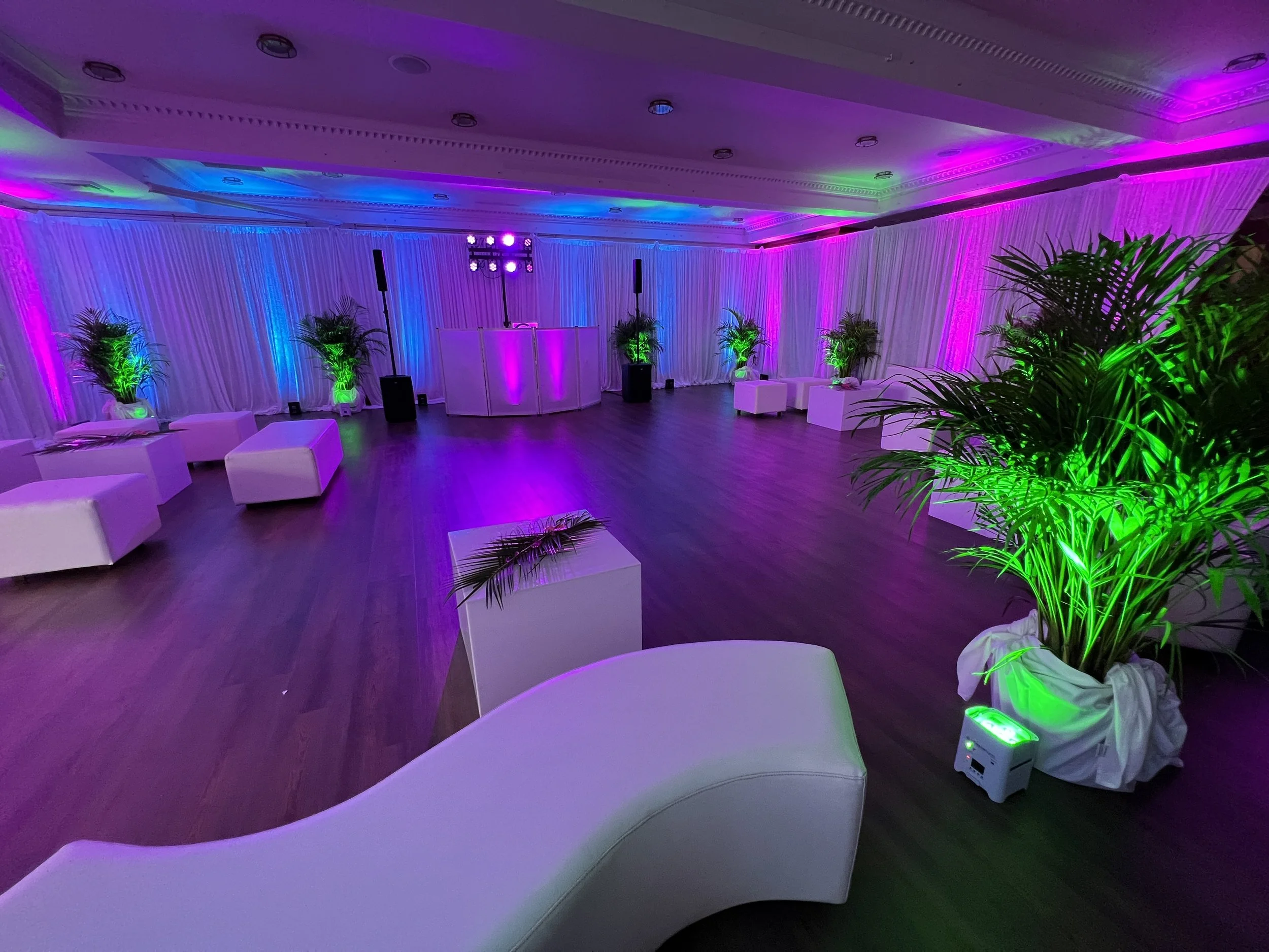 White lounge furniture under pink, green, and blue ambient uplighting in Sarasota