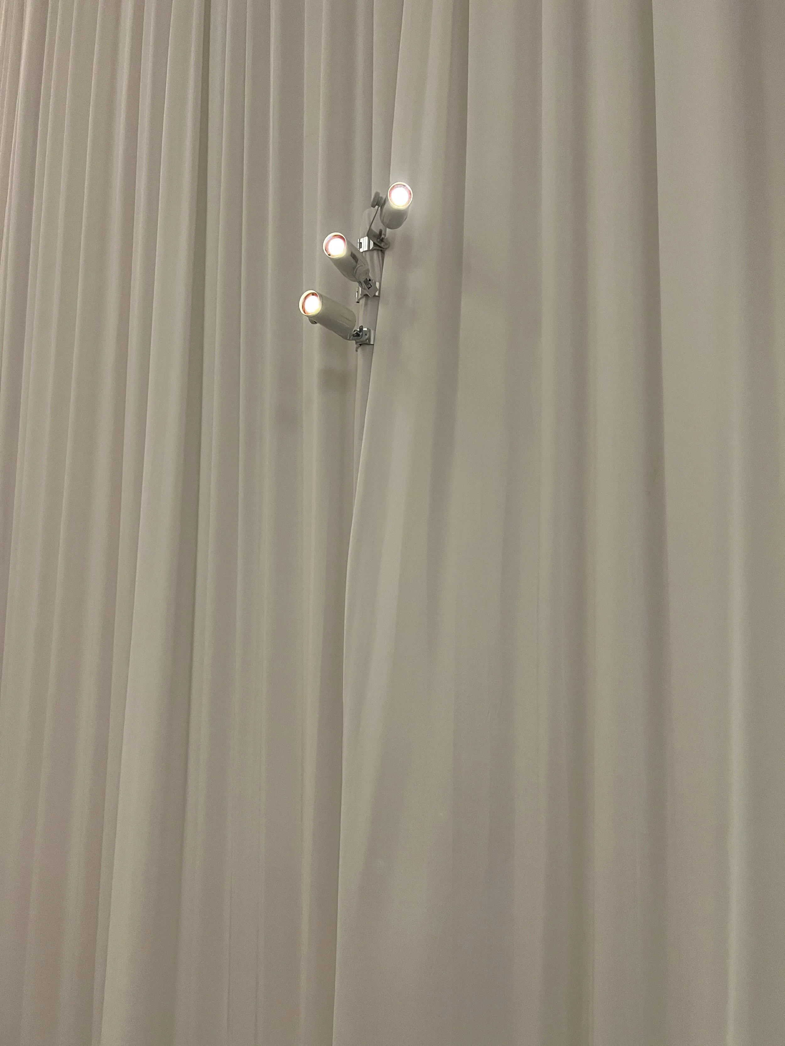 Close-up of ellipsoidal stage lighting fixtures mounted on white drape in Sarasota