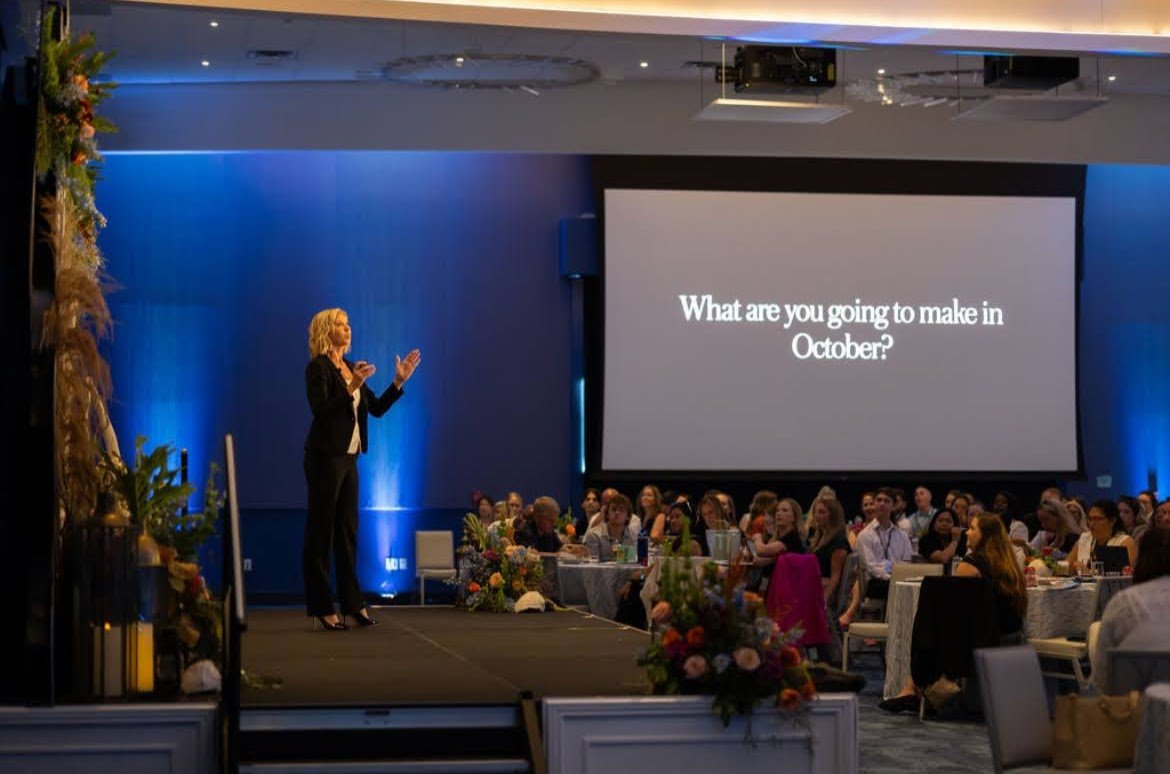 Corporate event production in Sarasota with blue stage lighting, large projection screen, and seated audience