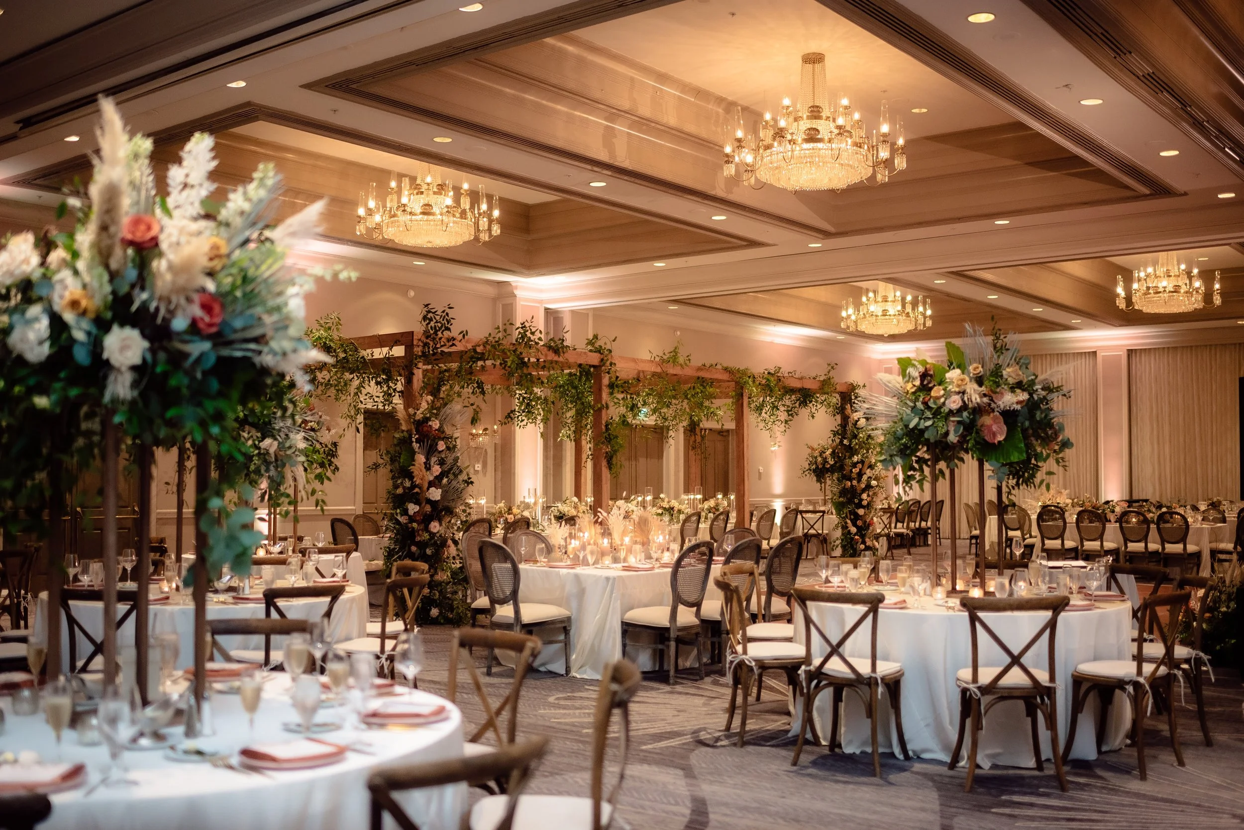 Ballroom with wooden arch structure, florals, and chandeliers in Southwest Florida