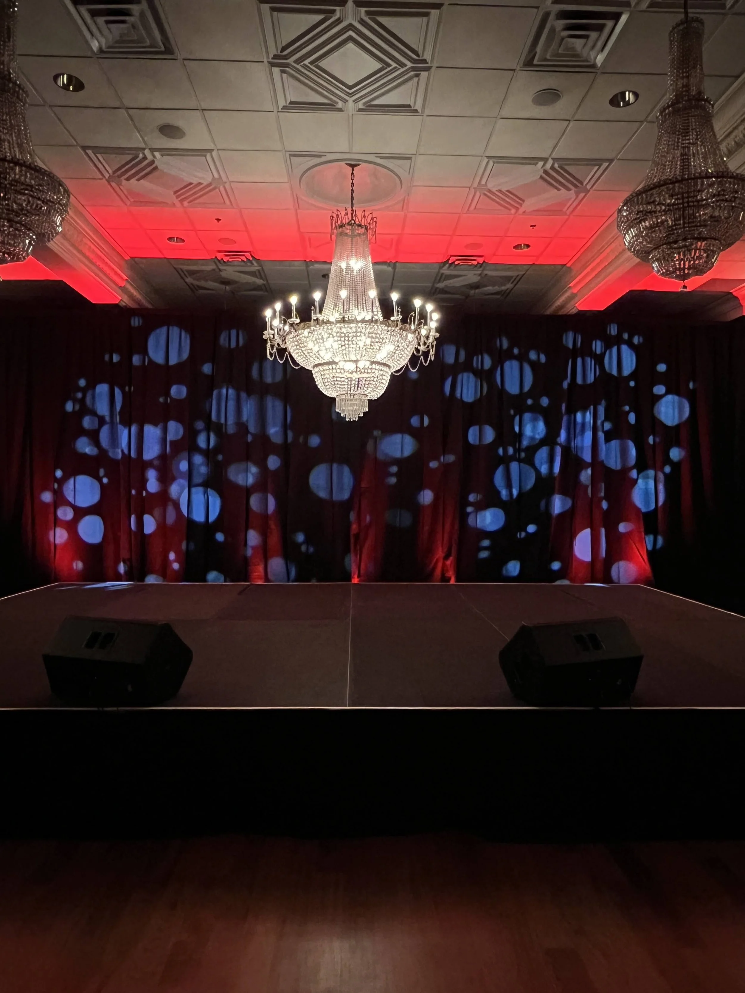 Polka dot gobo pattern lighting on a red curtain stage backdrop in Southwest Florida