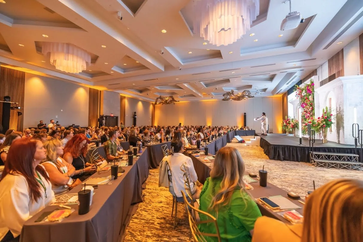 Large conference ballroom with chandeliers, stage, and seated audience in Southwest Florida