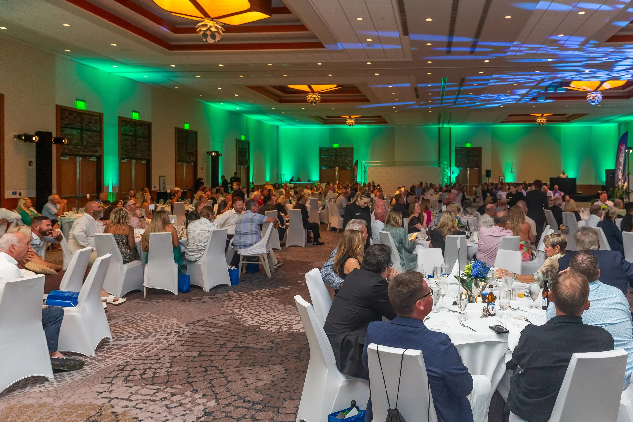Ballroom with green ambient uplighting and seated guests in Sarasota