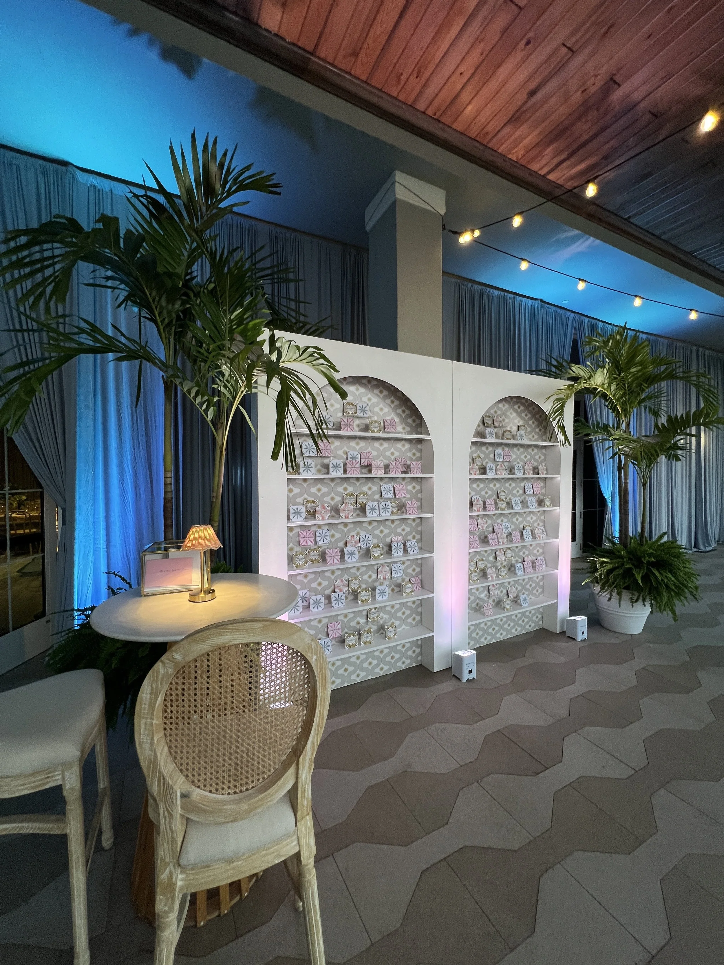 Escort card display with string lighting and palm accents in Sarasota