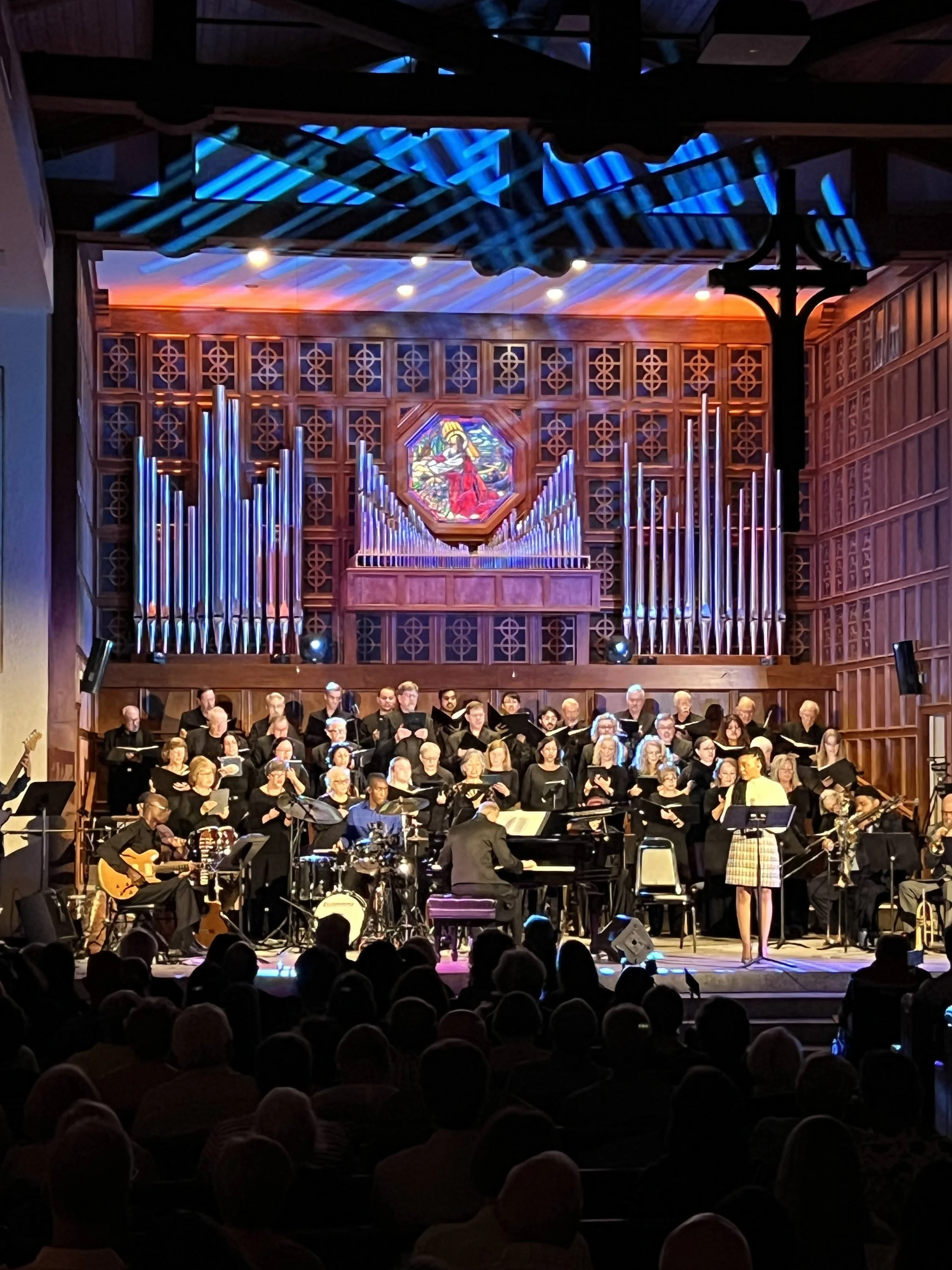 Close-up of choir and musicians performing under blue-lit organ pipes in Southwest Florida