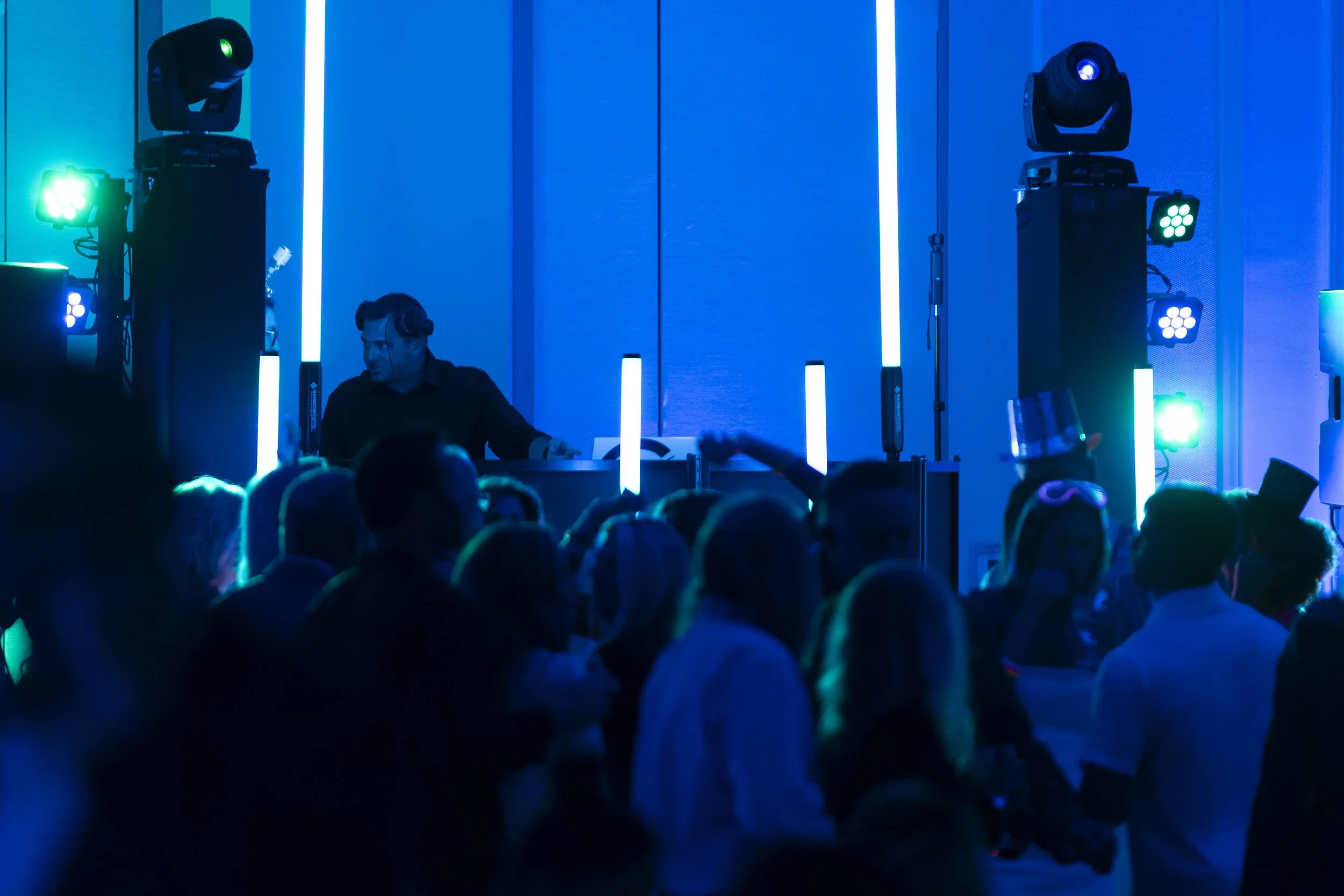 DJ booth with blue and green moving head lights over a dance crowd in Sarasota