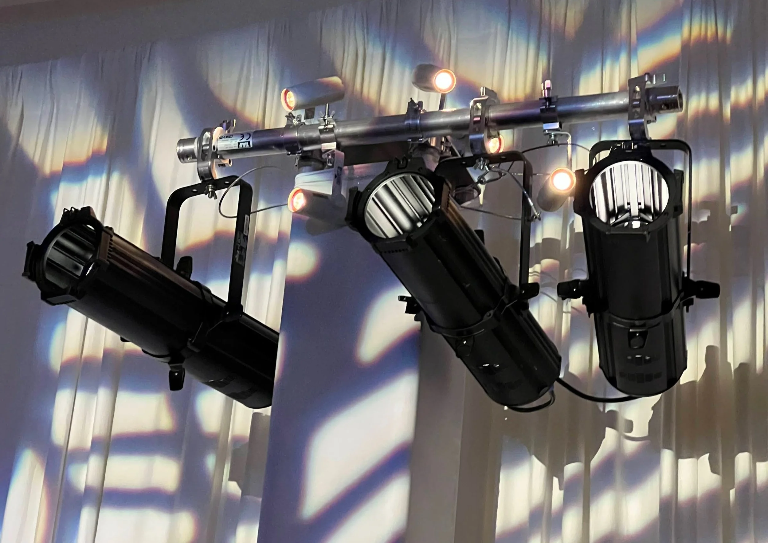 Close-up of ellipsoidal/Leko stage lighting fixtures on white drape in Sarasota