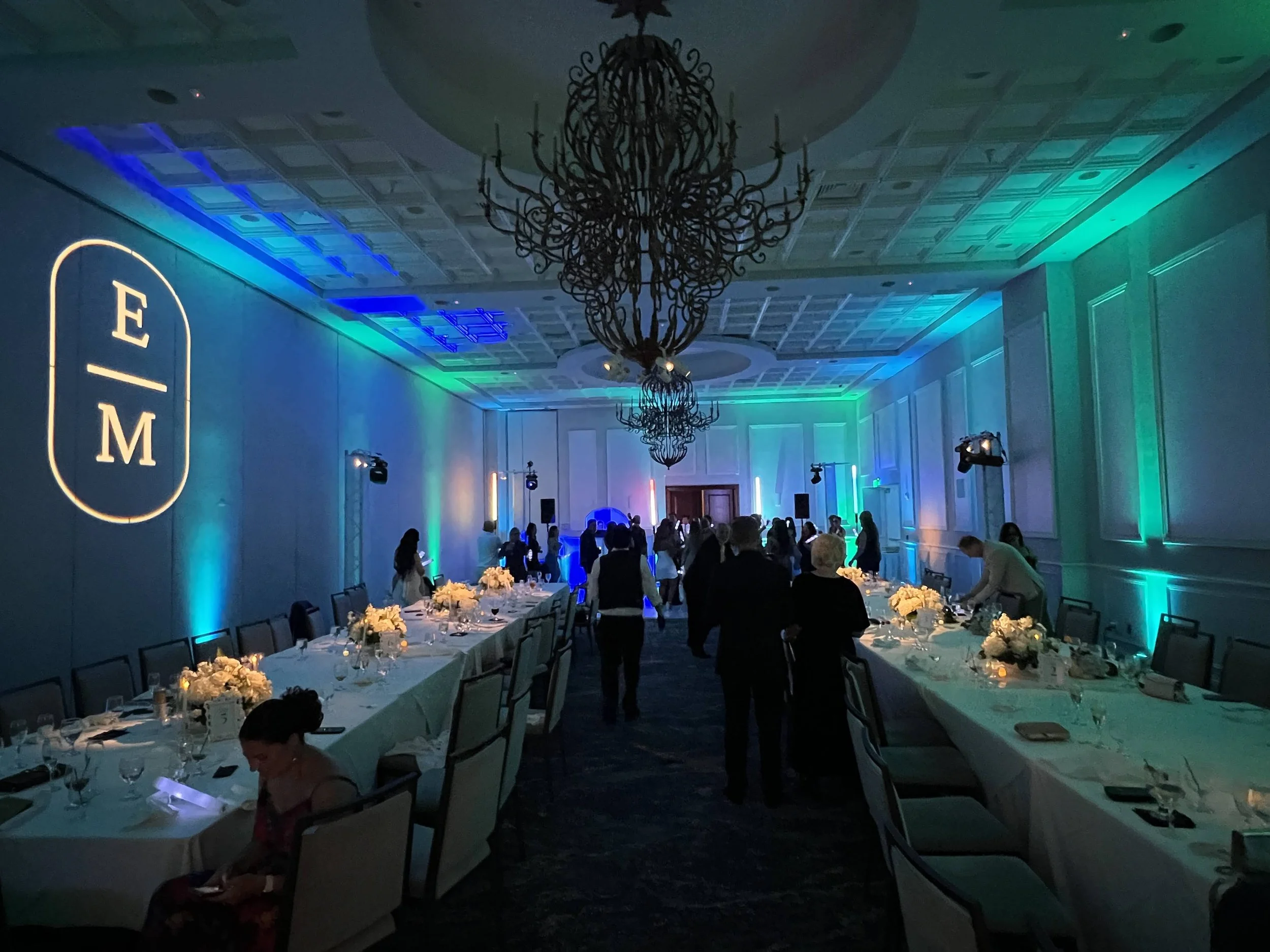 Monogram gobo projection with teal uplighting over a long candlelit table in Sarasota