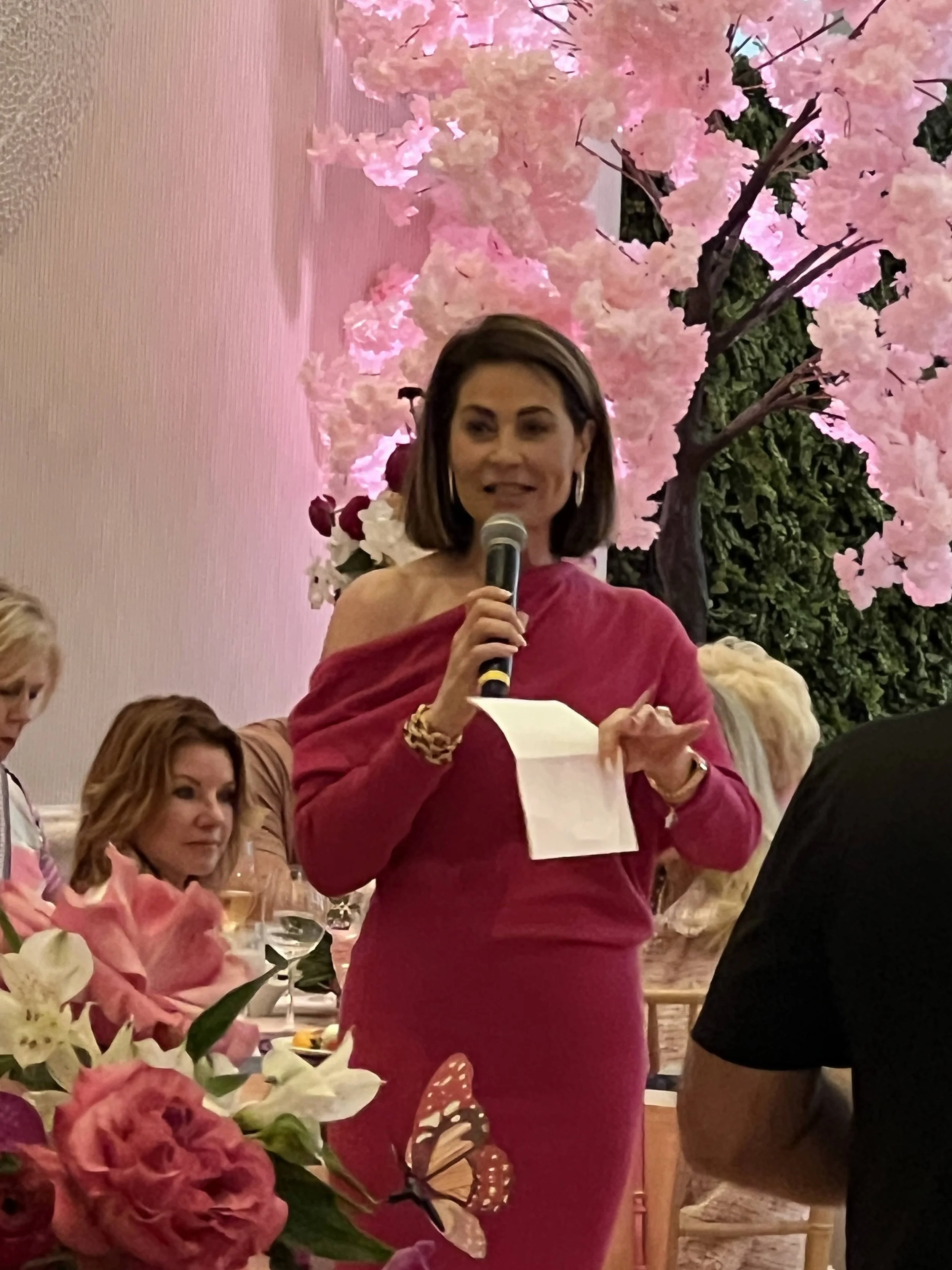Speaker on stage with floral backdrop and ambient lighting at a gala in Sarasota