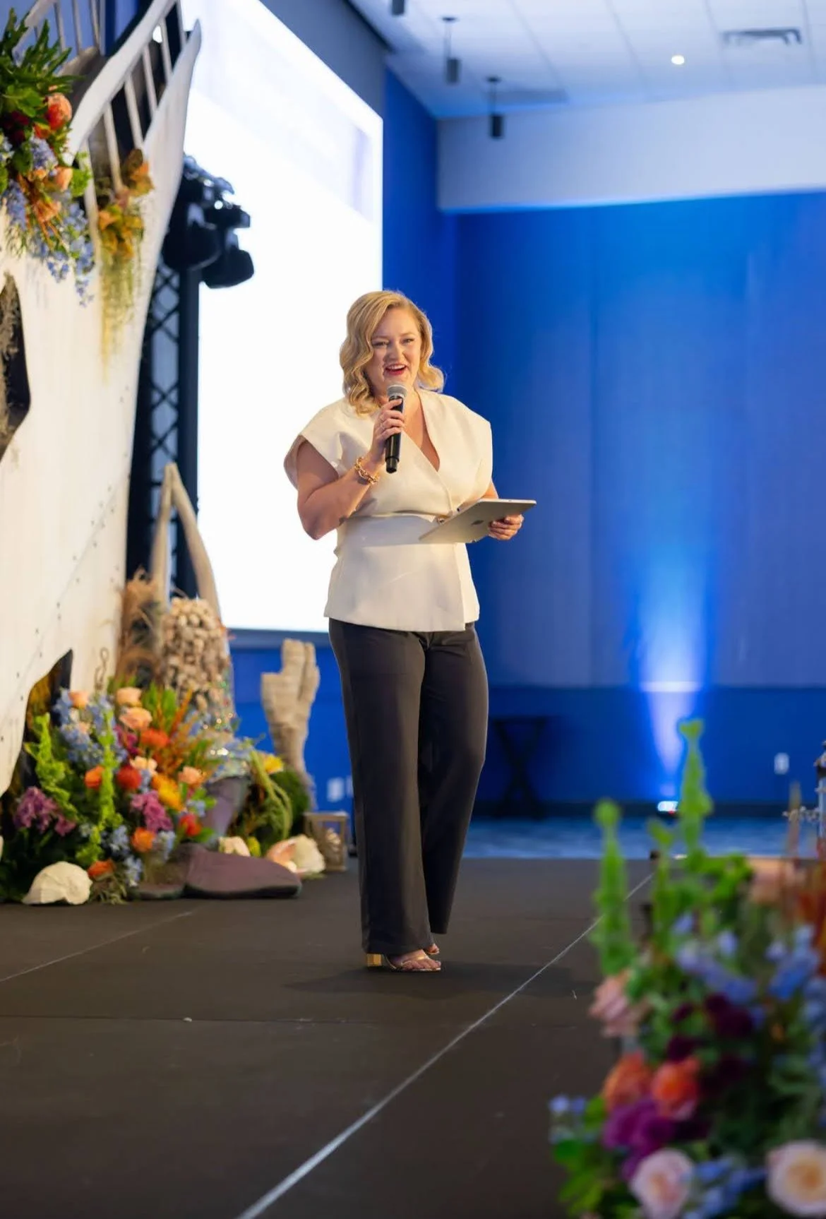Blue stage lighting and floral design for a speaker event in Southwest Florida