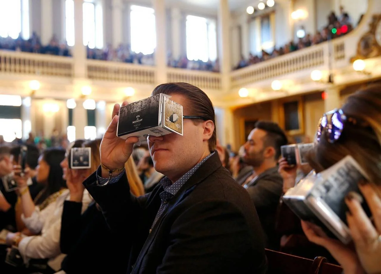 Man using cardboard viewfinder at Forbes event.