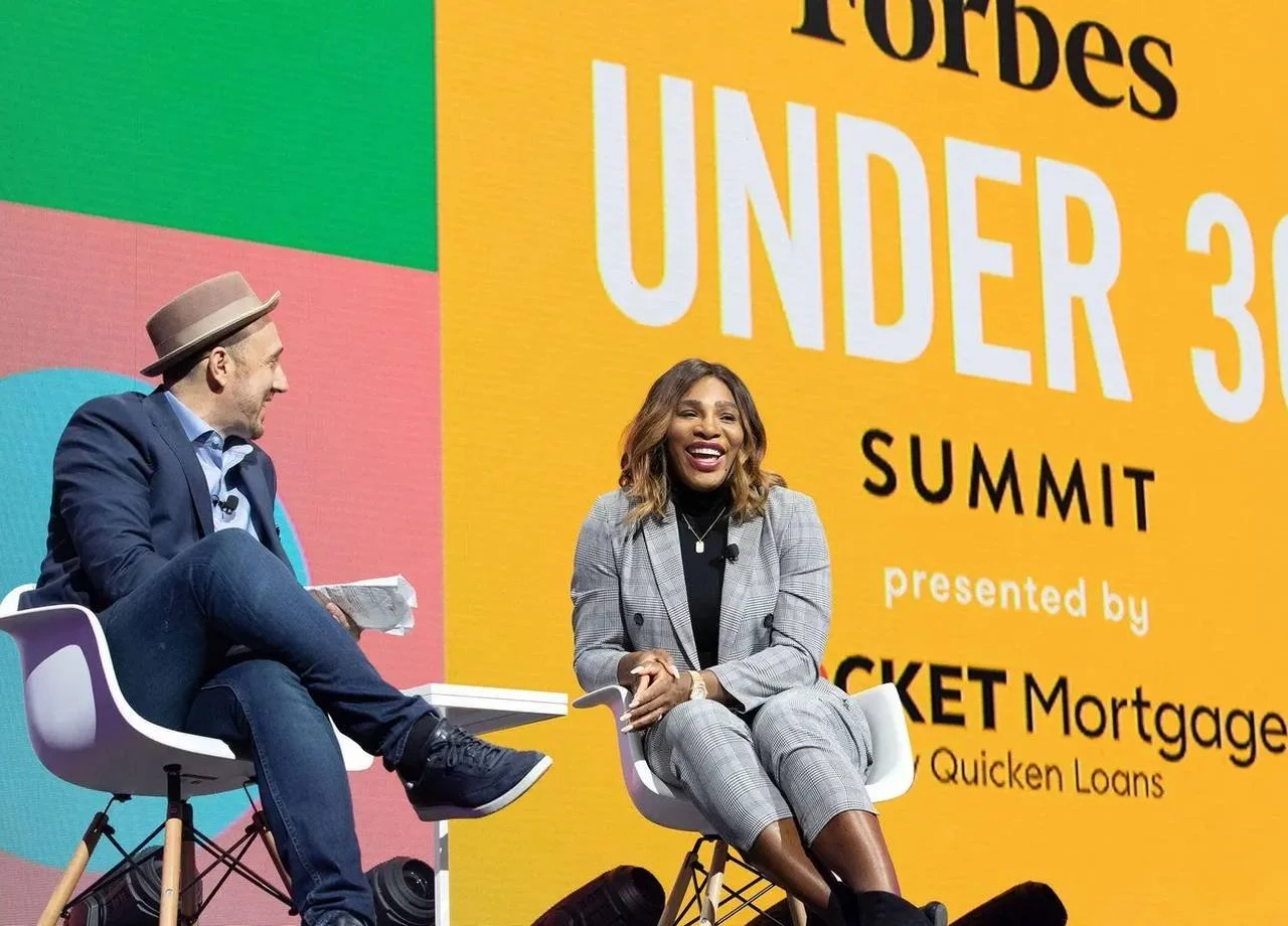 Two speakers share a laugh during an onstage interview at the Forbes Under 30 Summit
