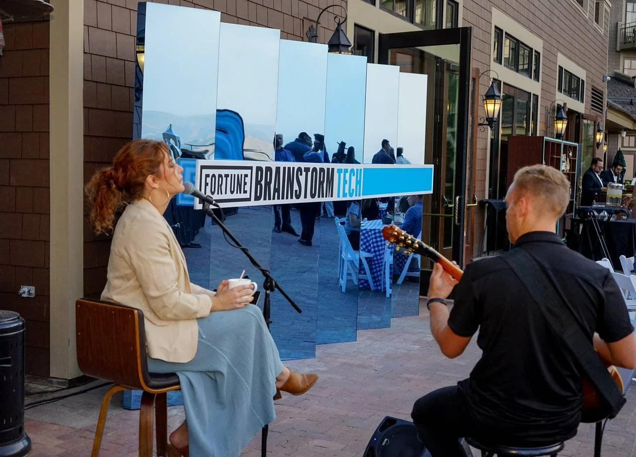 Woman strumming on an acoustic guitar at Fortune Brainstorm