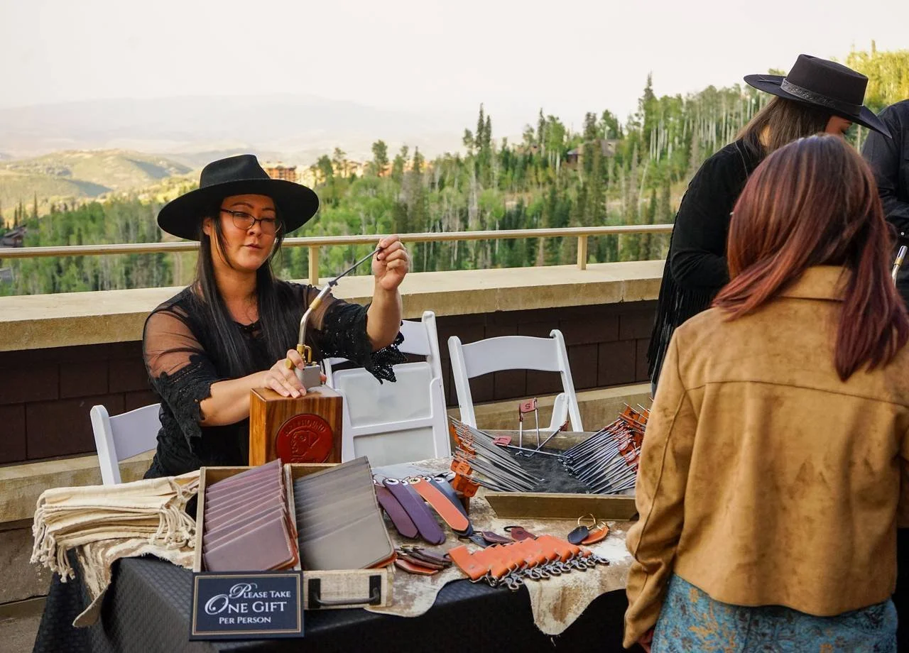 Woman providing leather stamping service at event table