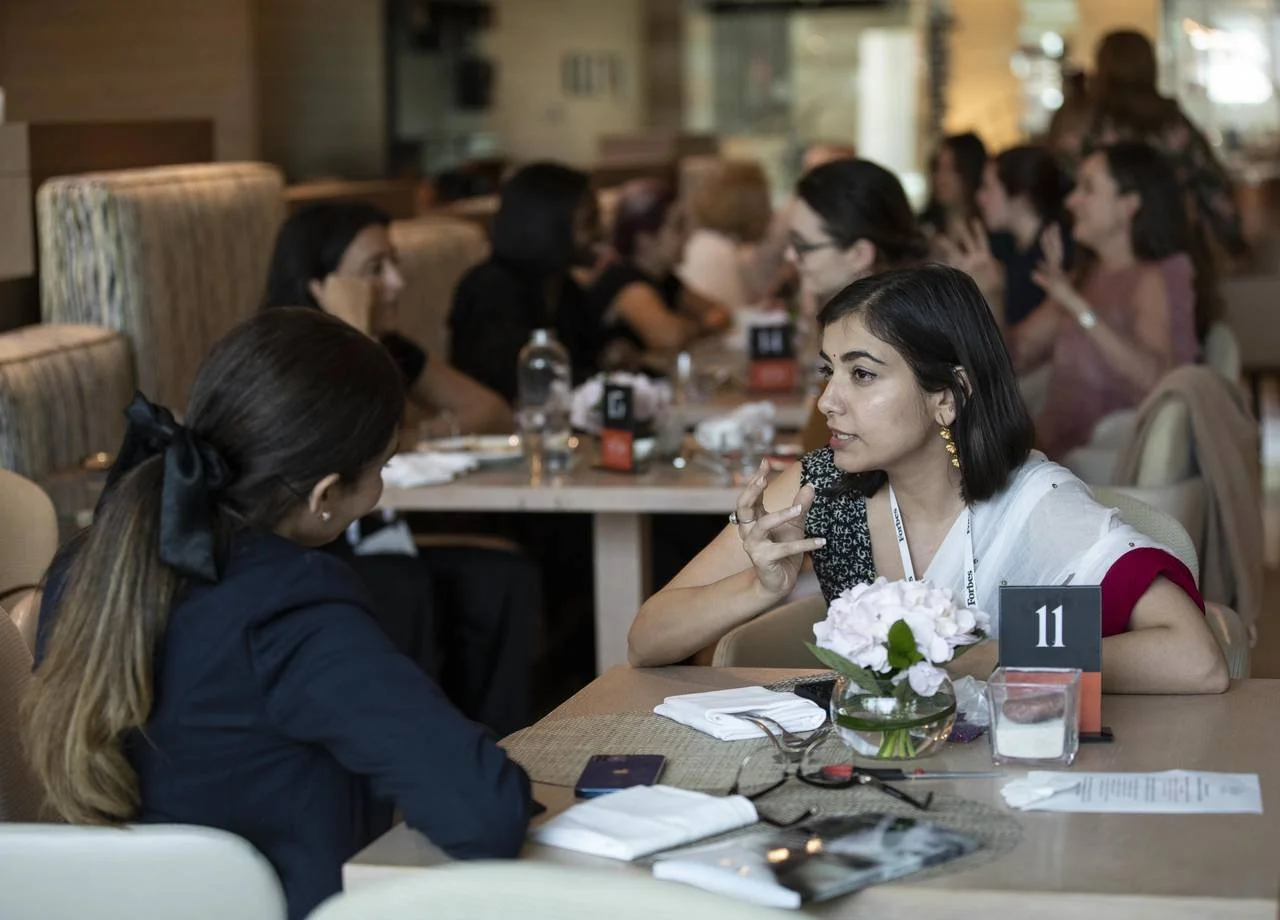 Two women talking at lunch table during a Forbes event