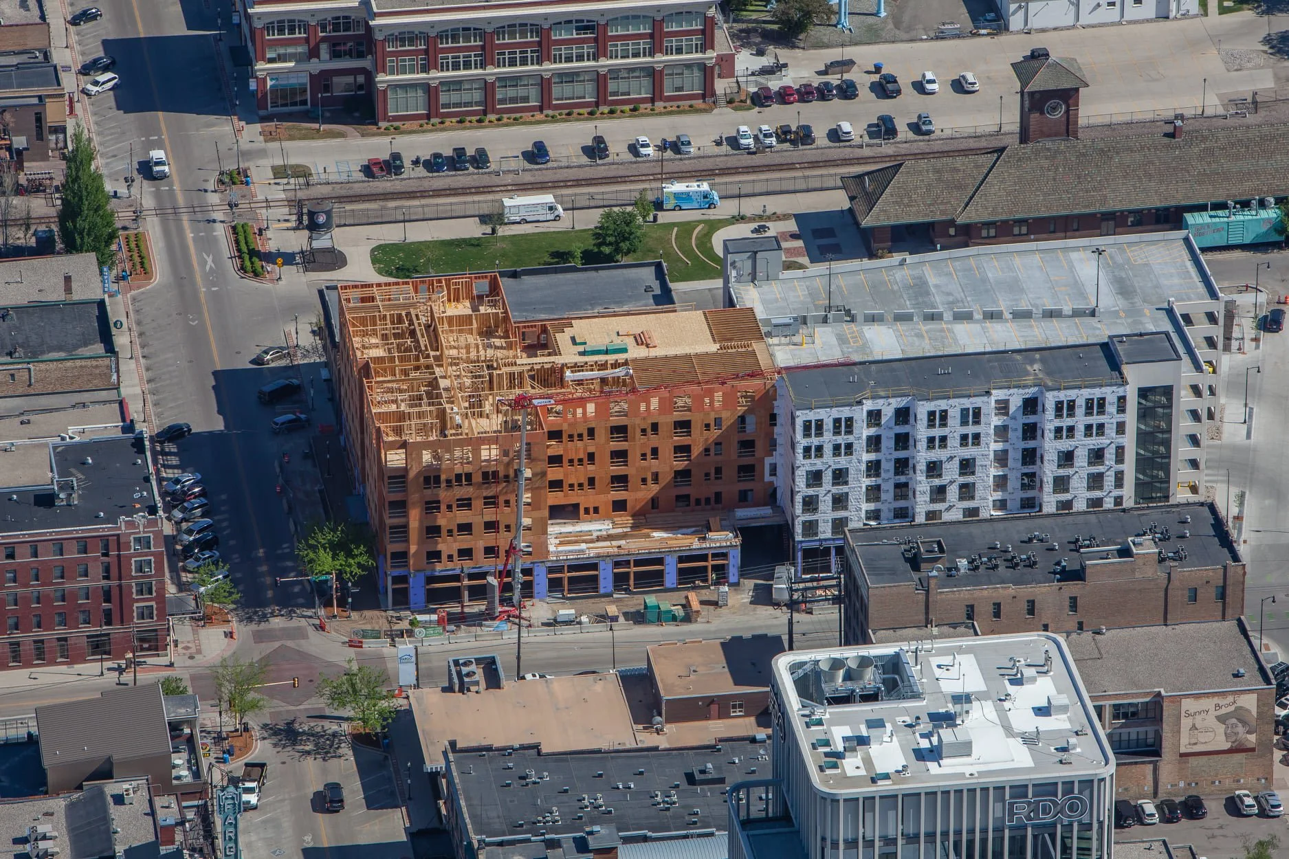 Under construction multi-story building with multiple cranes and construction equipment on a clear day.