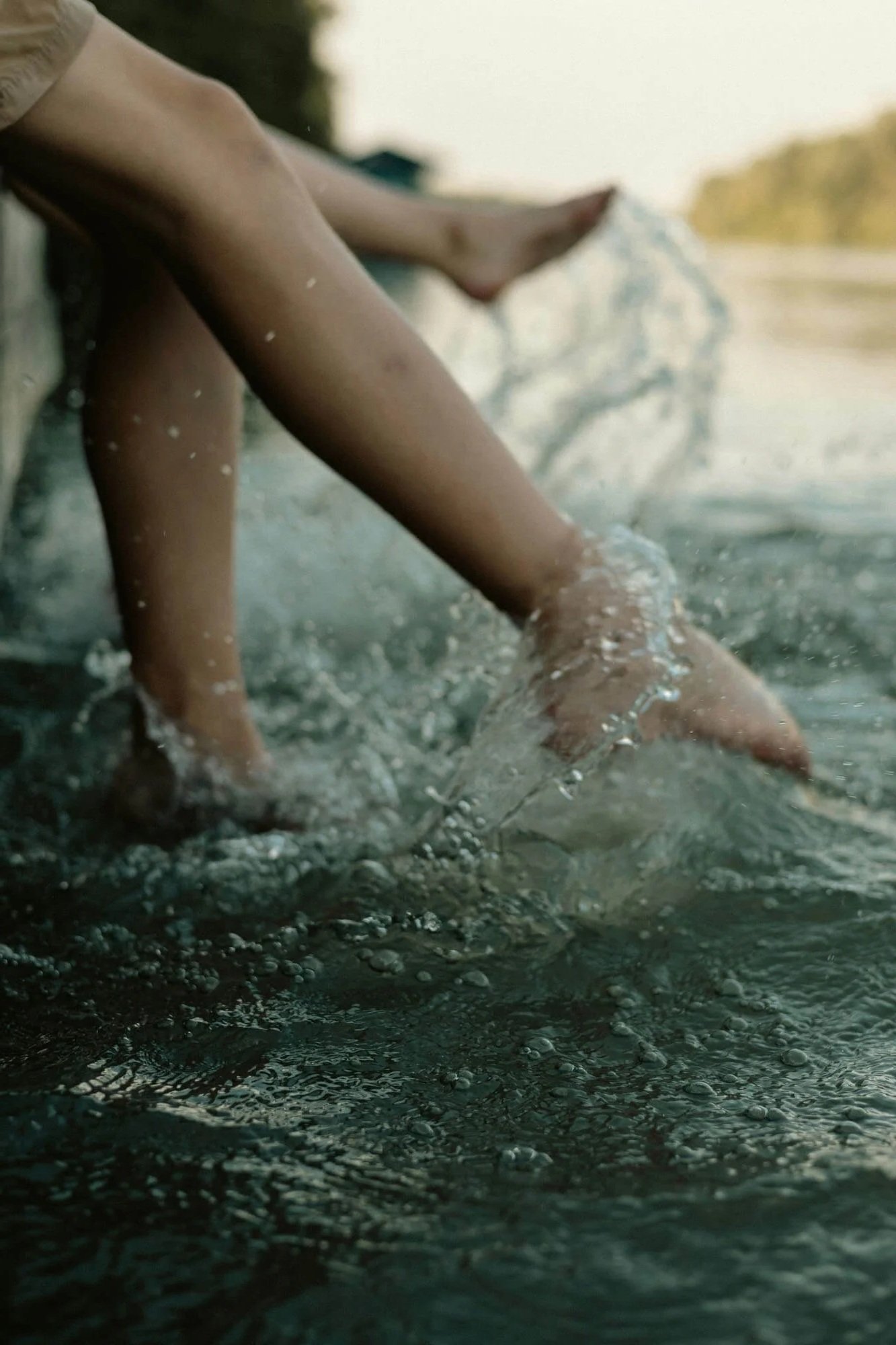 Close-up of a child playing in water, with hands submerged and water splashing around.