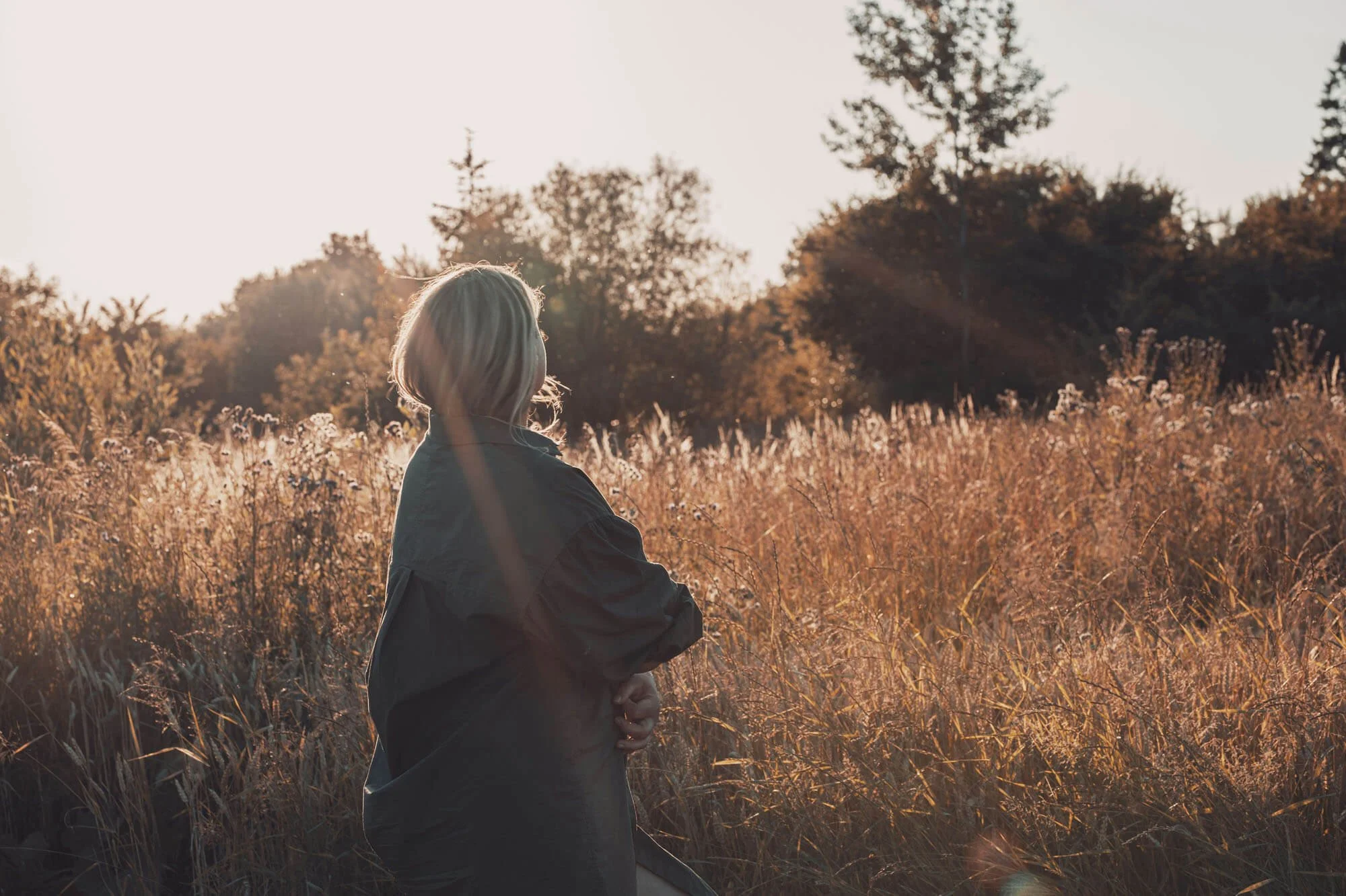 Person standing in field with sun shining on them