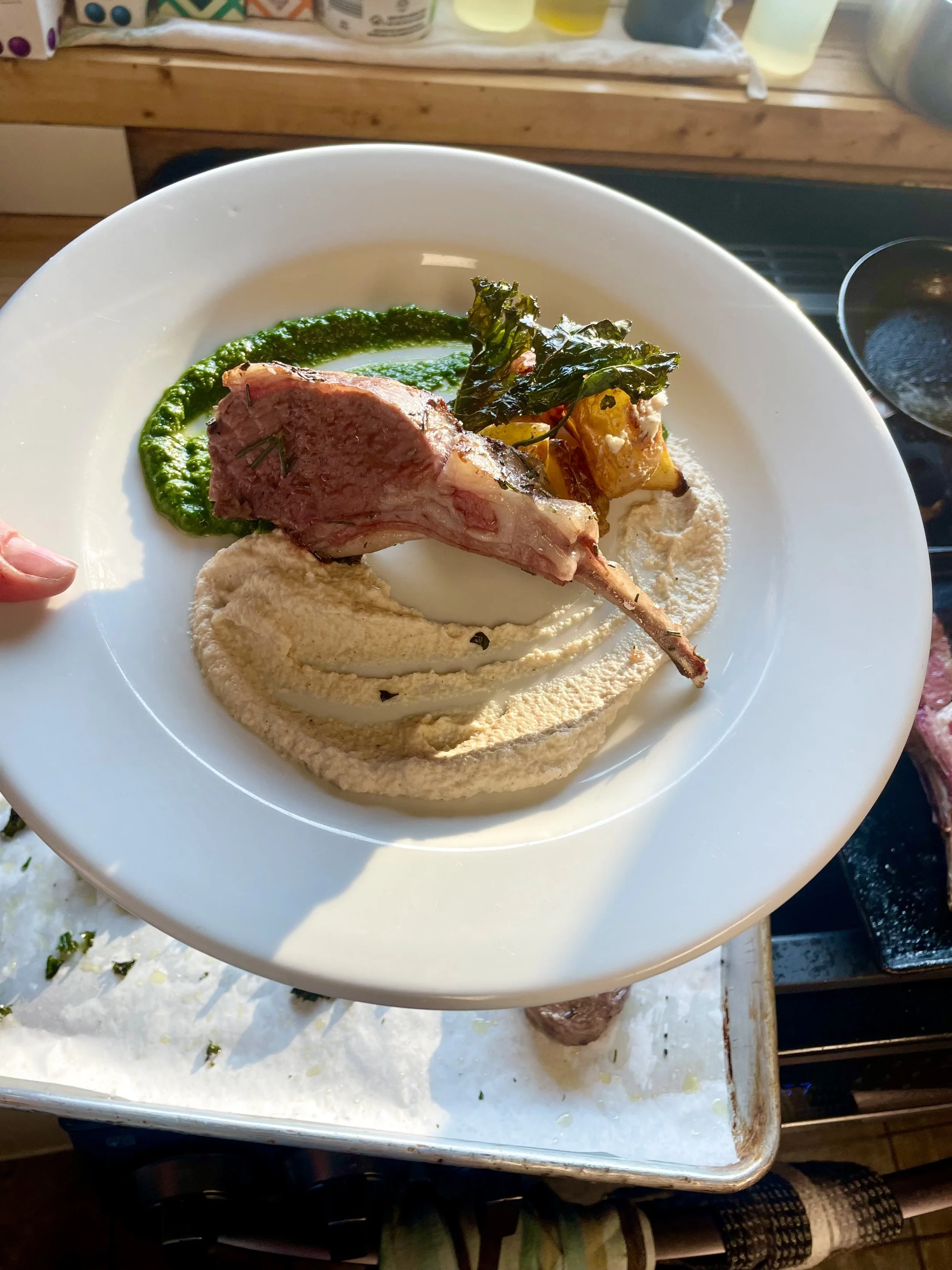 Herb-crusted rack of lamb over creamy puree with roasted vegetables, plated by a private chef in Revelstoke.
