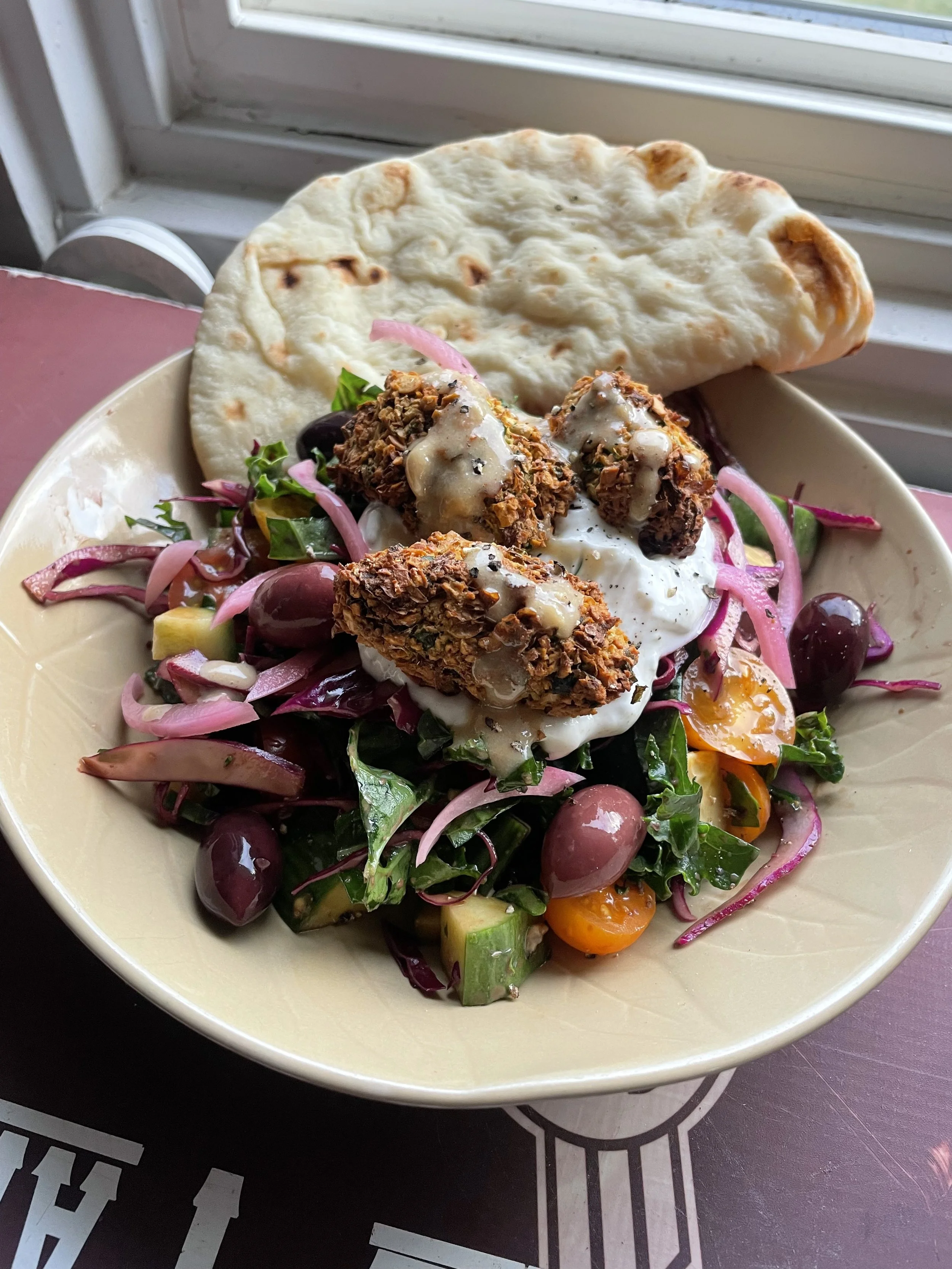 Crispy chicken salad bowl with pickled onion, olives and warm flatbread, a hearty meal after a day on the slopes in Revelstoke.