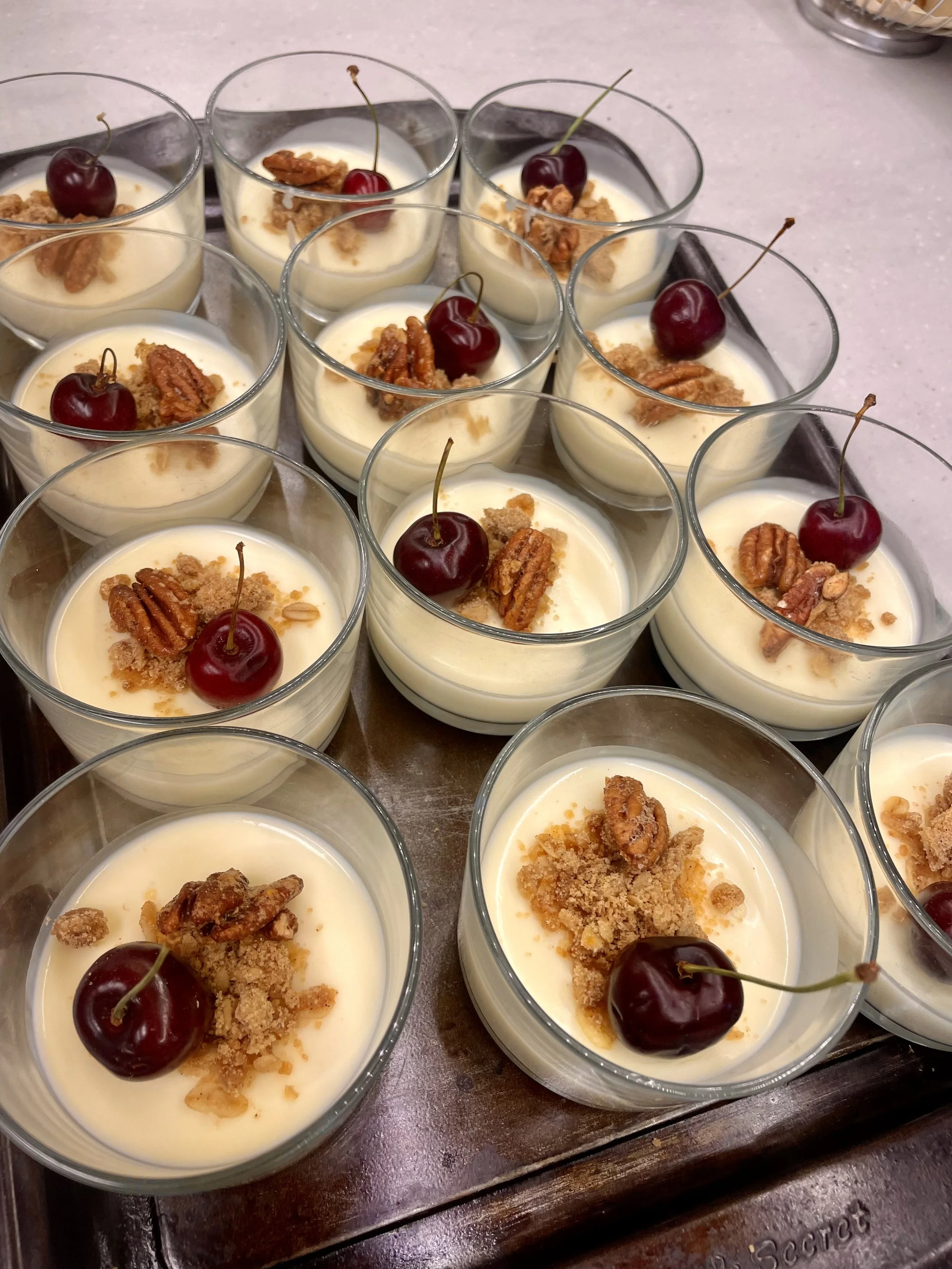 A tray of individual dessert cups filled with creamy pudding, topped with cherries, pecans, and crushed cookies prepared by a Revelstoke private chef.