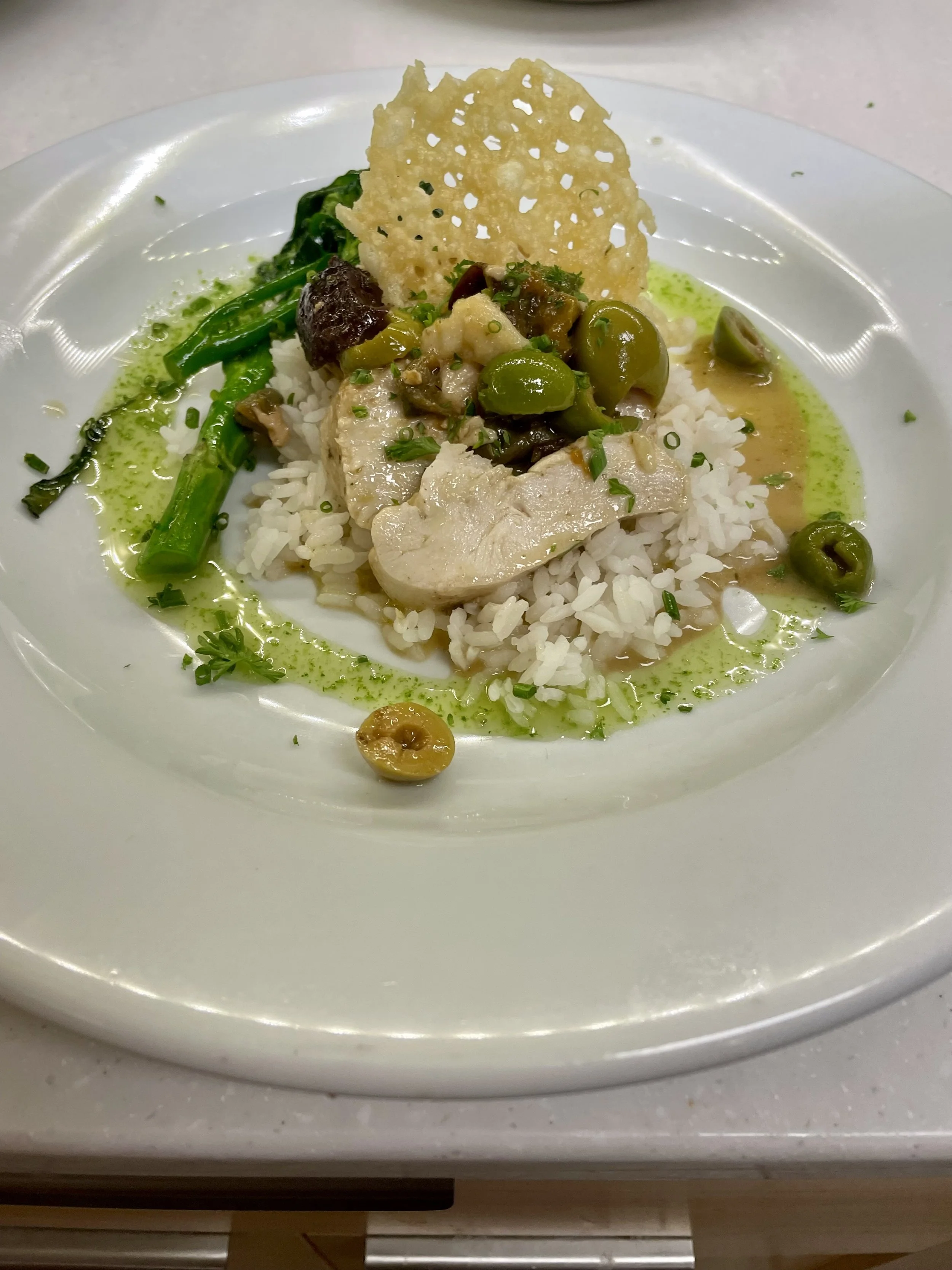 Pan-seared fish over rice with herb sauce, olives and broccolini, fine dining catering in Revelstoke.
