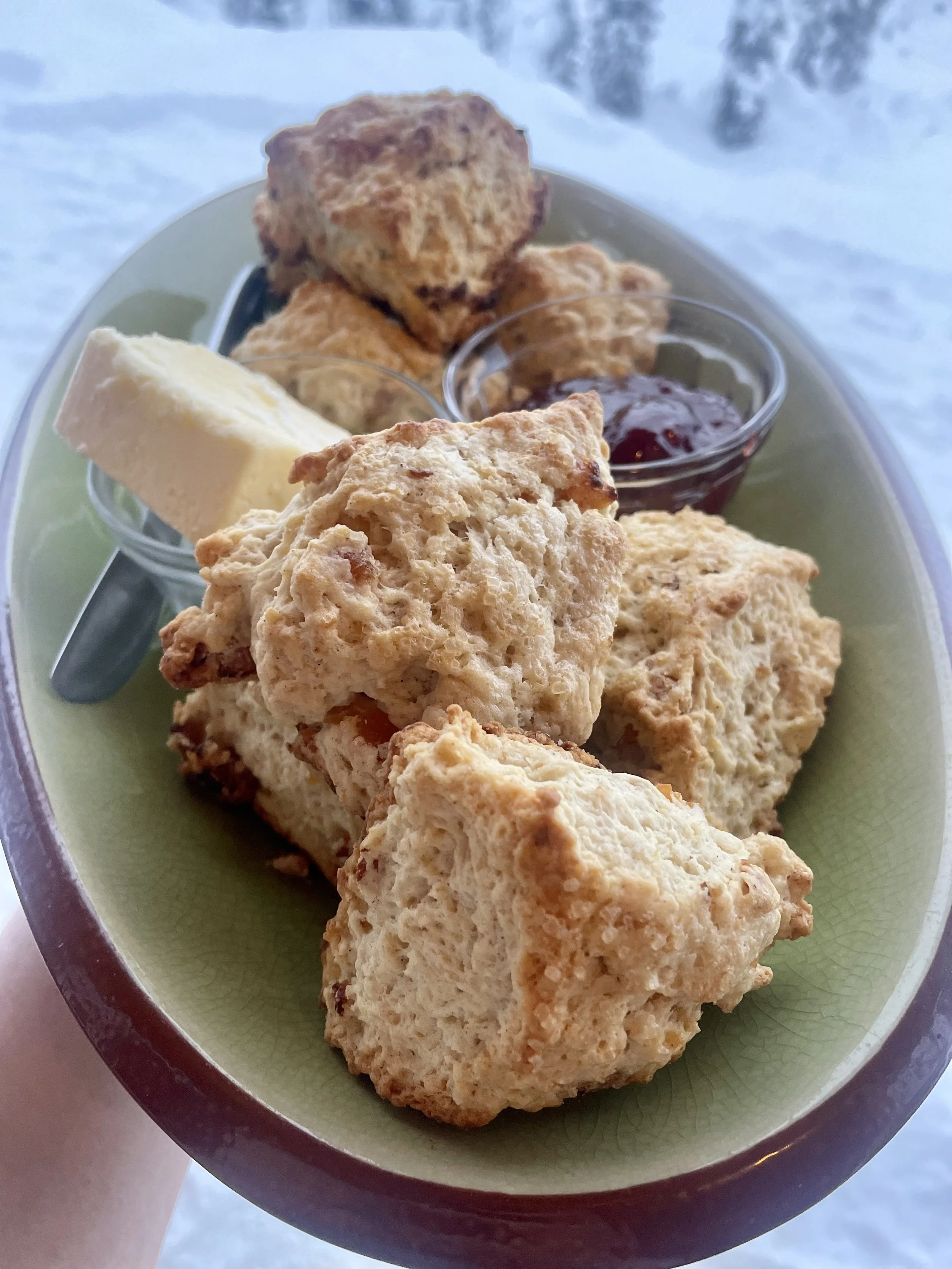A plate of scones with a small dish of jam and a piece of butter prepared by a Revelstoke private chef.