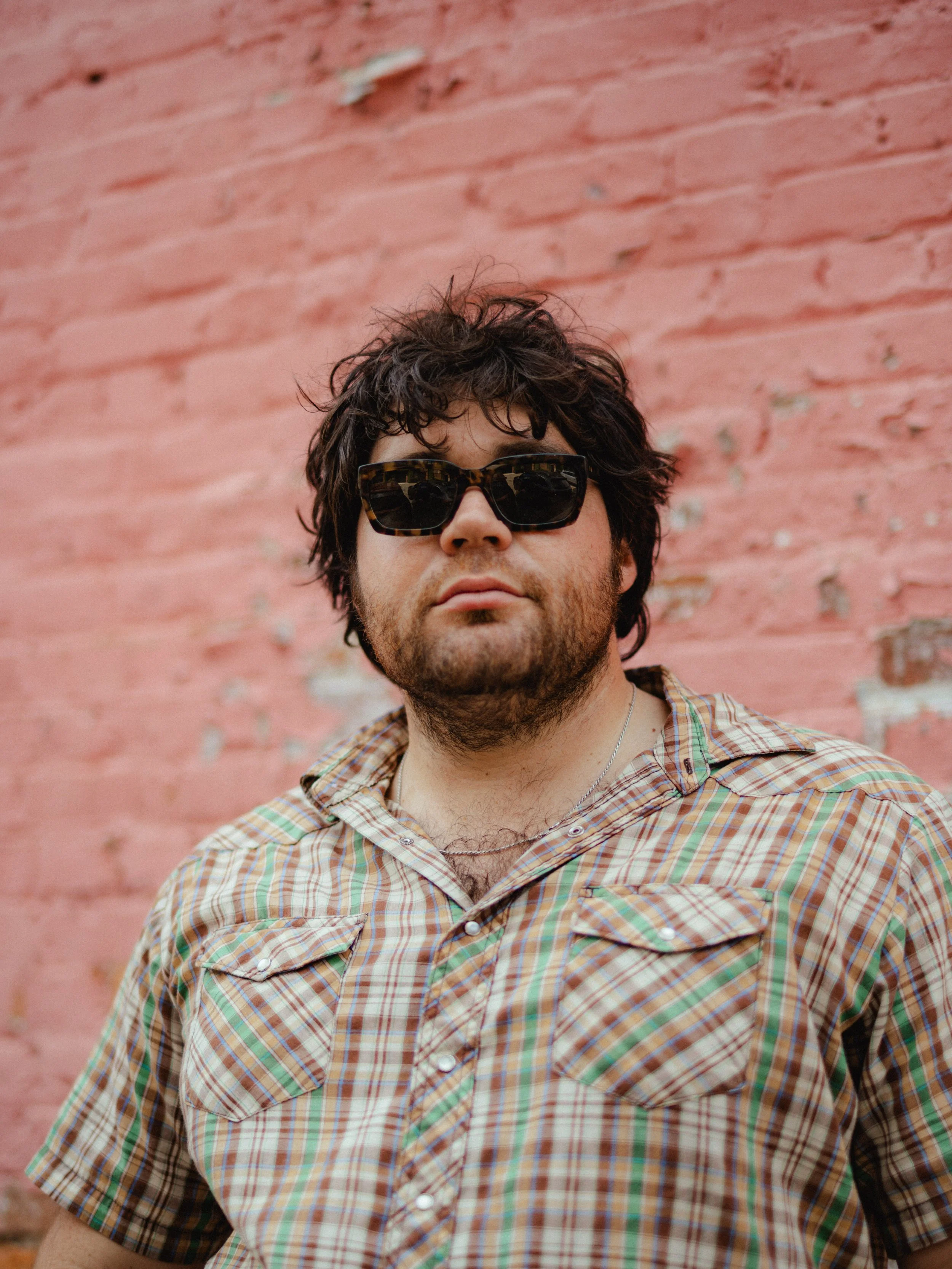 Jalen Reyes in front of a dark pink brick wall.