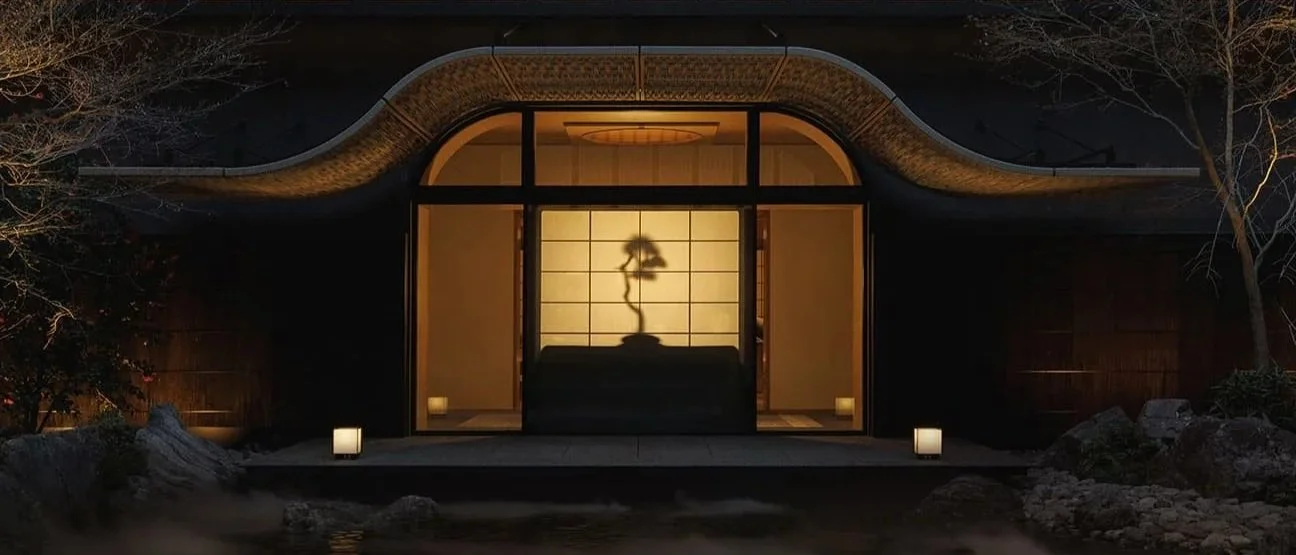 Night view of a modern Japanese-style house with illuminated entrance, featuring a shoji screen door, a bonsai tree silhouette shadow, and soft outdoor lighting.