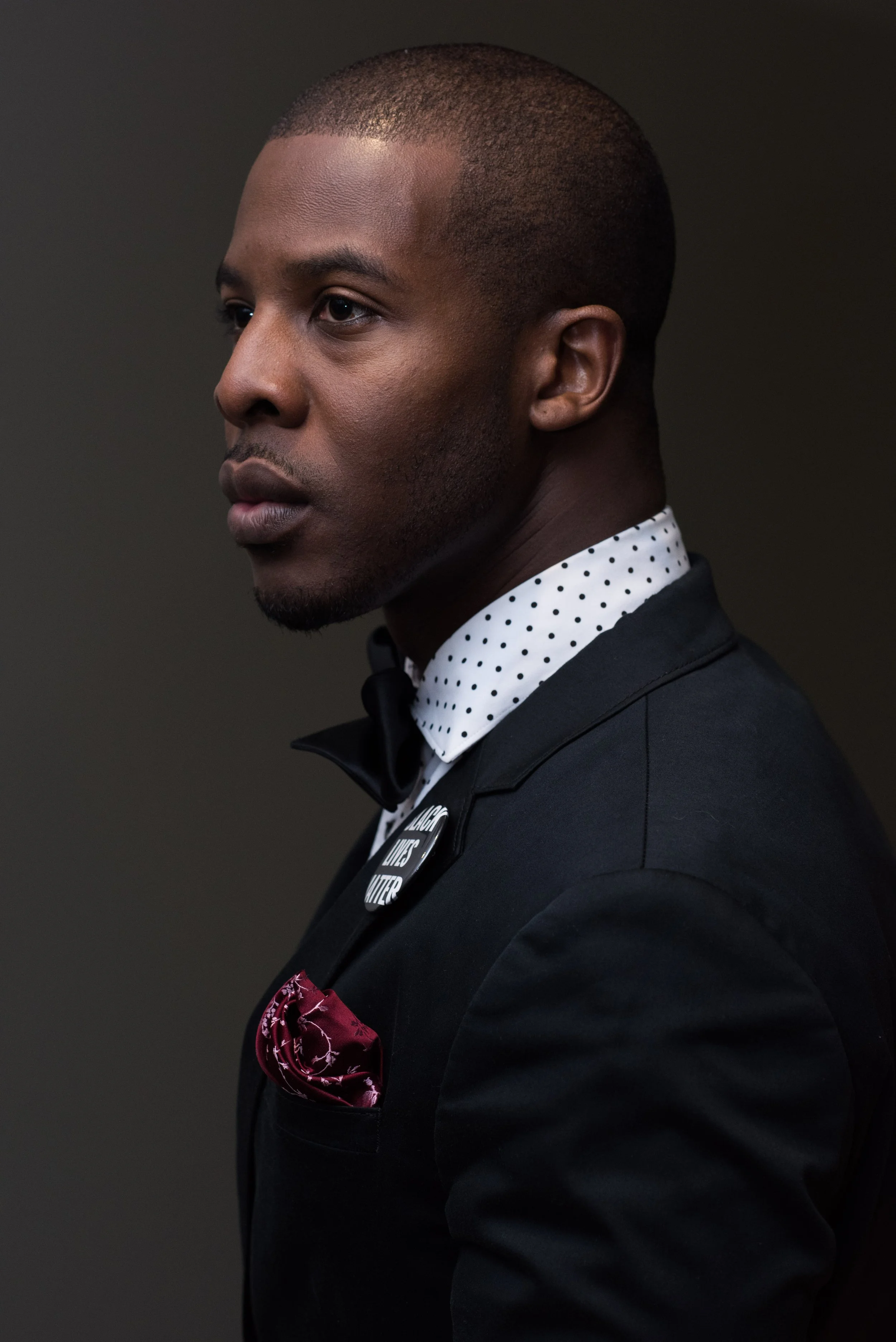 Carver Ealy, M.Ed. in profile in a black blazer, red pocketsquare, and black bowtie.