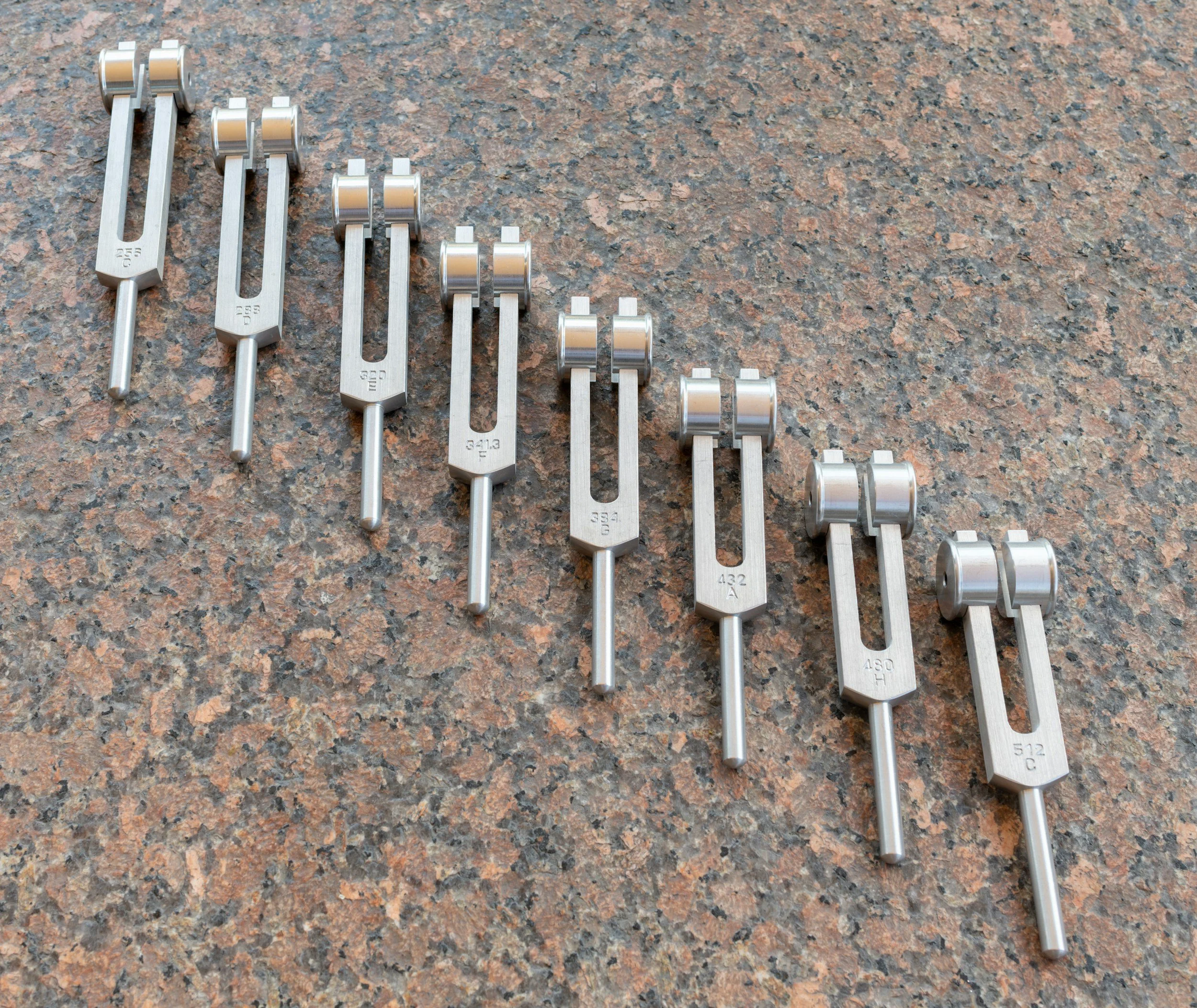 Set of precision feeler gauges with metal blades of varying thickness laid out on a rough stone surface.