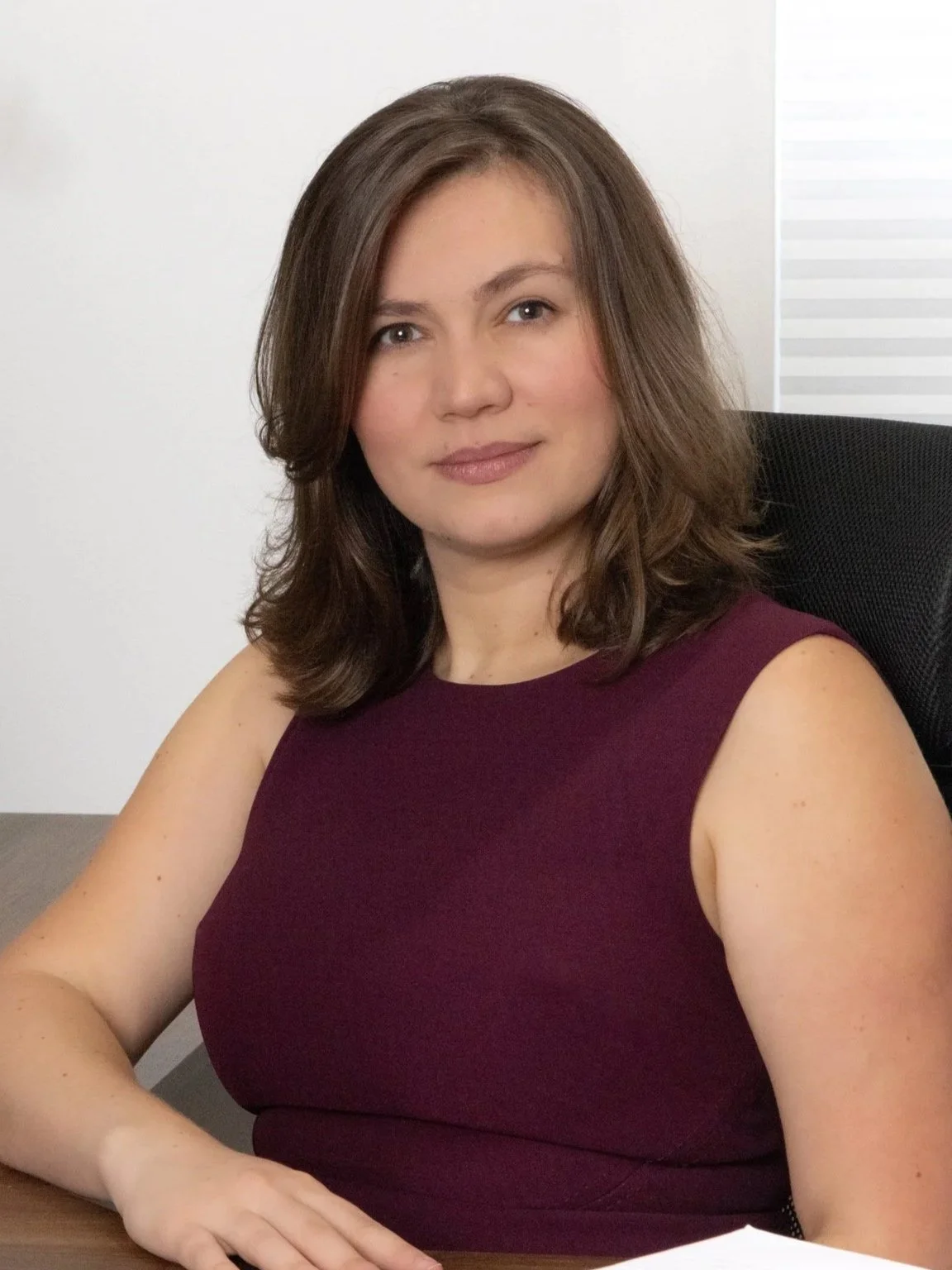 Yulianna Fedorchak, MSN, APRN, FNP-C, CCRN, founder of Dedicated Legal Nurse Consulting, seated at her desk