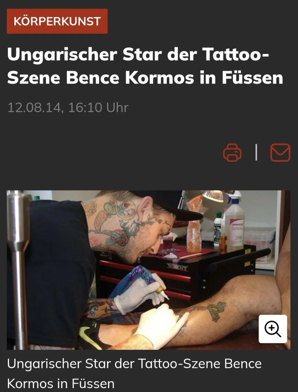 A tattoo artist with tattoos on his neck and hands, wearing a black shirt, tattooing a client's leg in a tattoo studio with tattoo supplies on the counter.